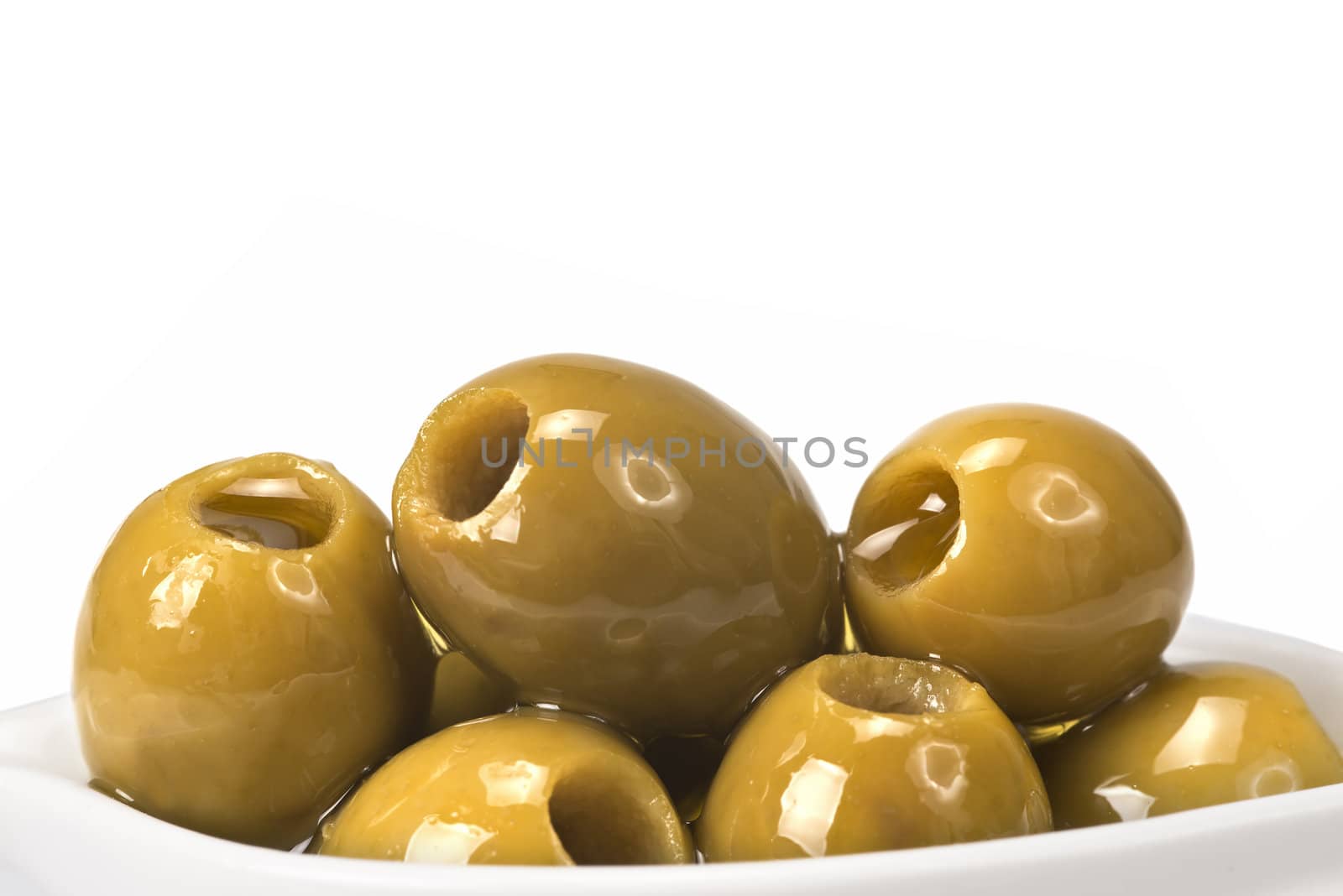 Pitted olives in a saucer isolated on a white background.