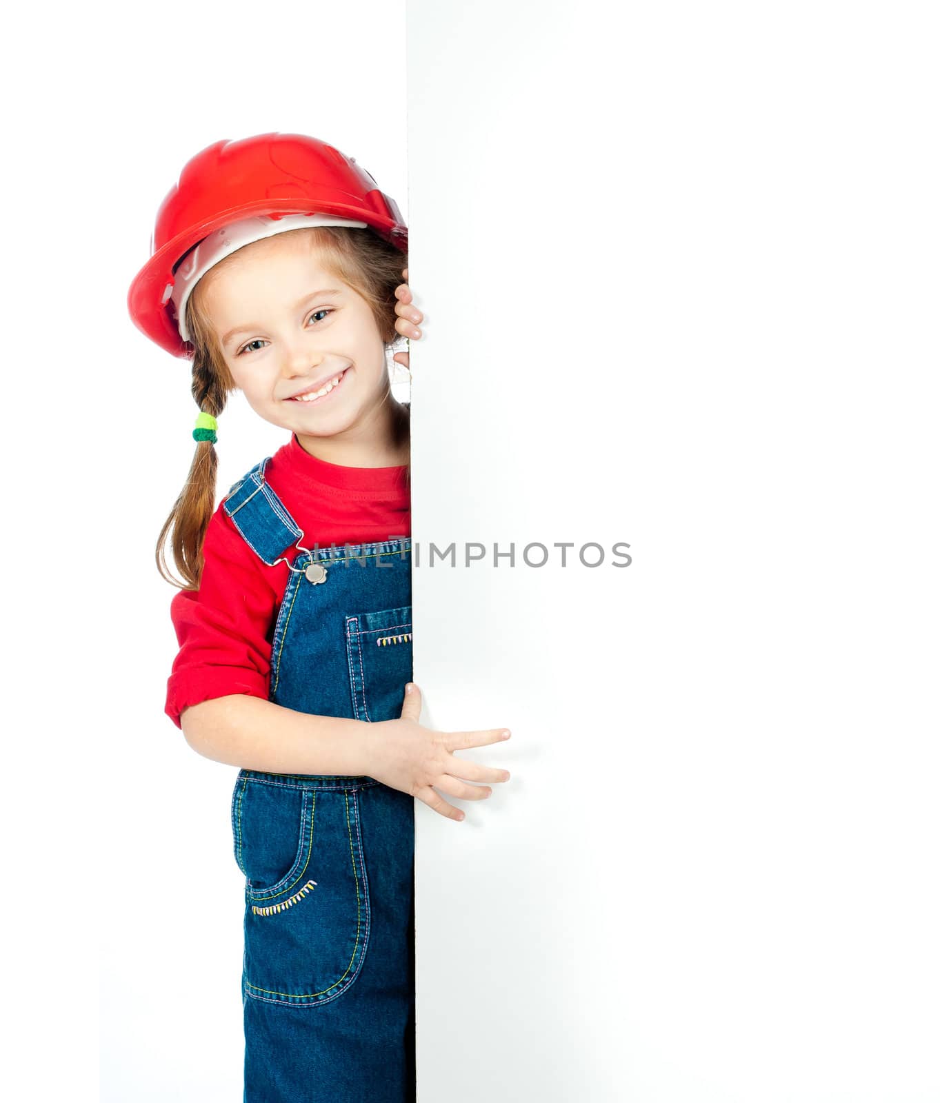 smiling little girl in the construction helmet with a white board