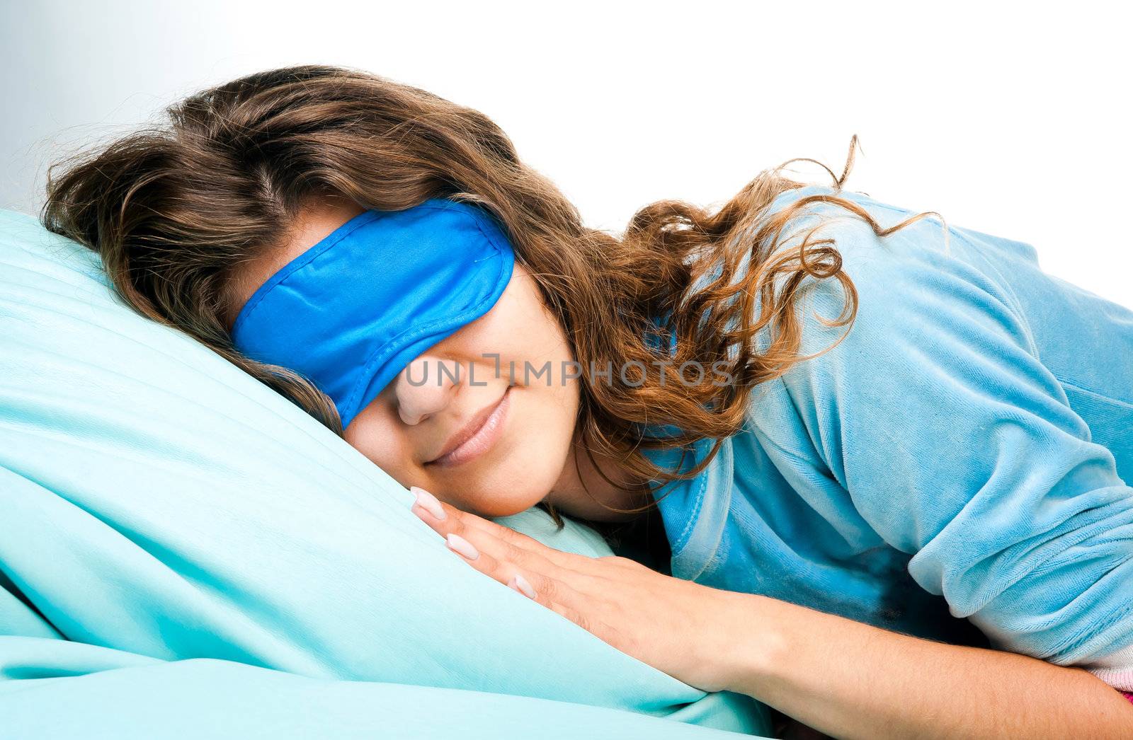 Beautiful sleeping young woman in sleep eye mask on blue furnishing