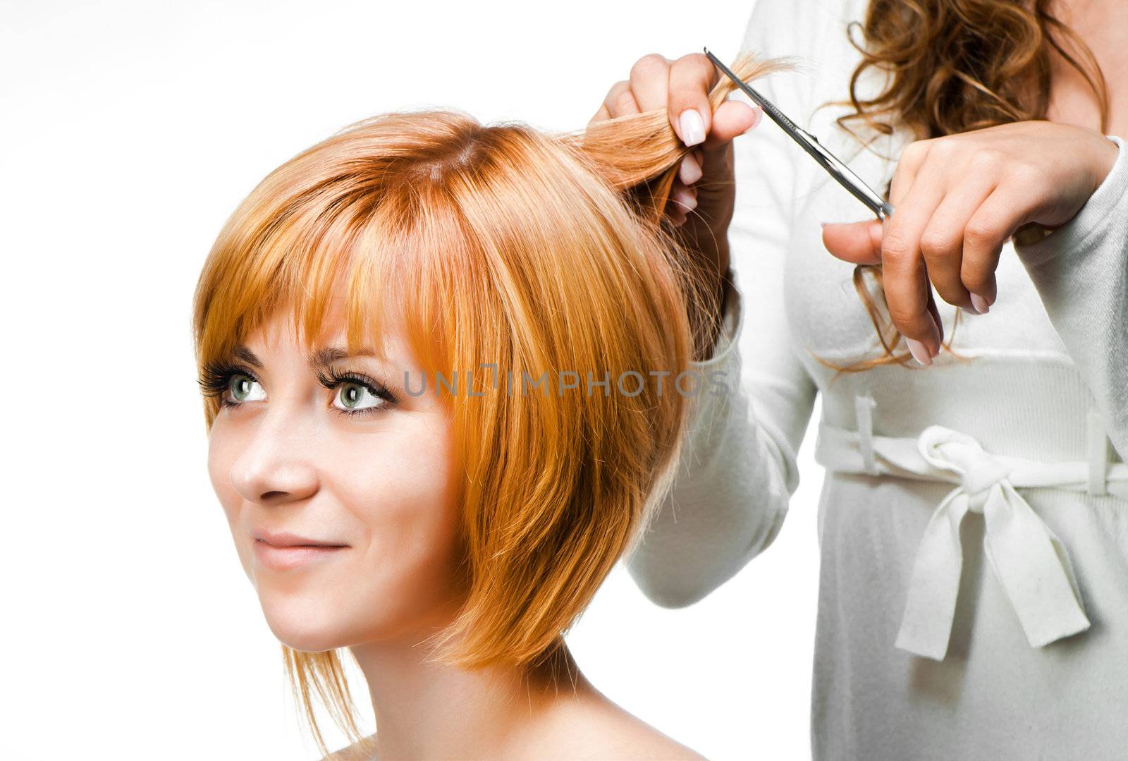 Young woman barber makes hairstyle for a girl close up