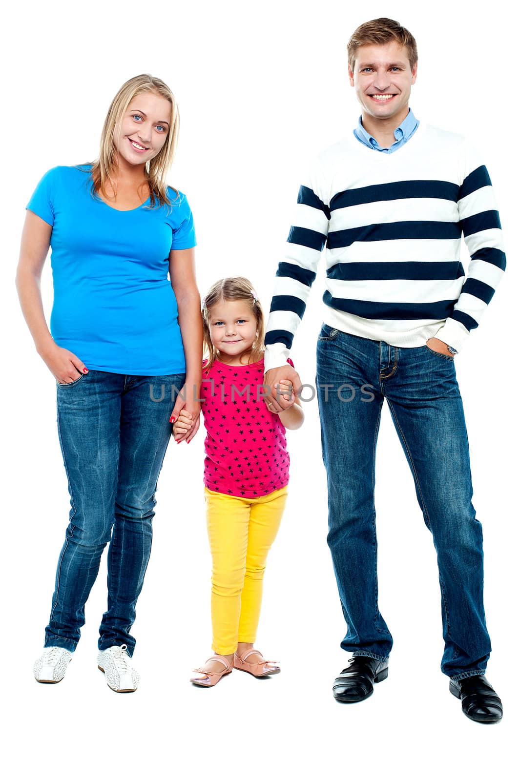 Sweet little kid standing in between her parents and holding their hands. Full length portrait