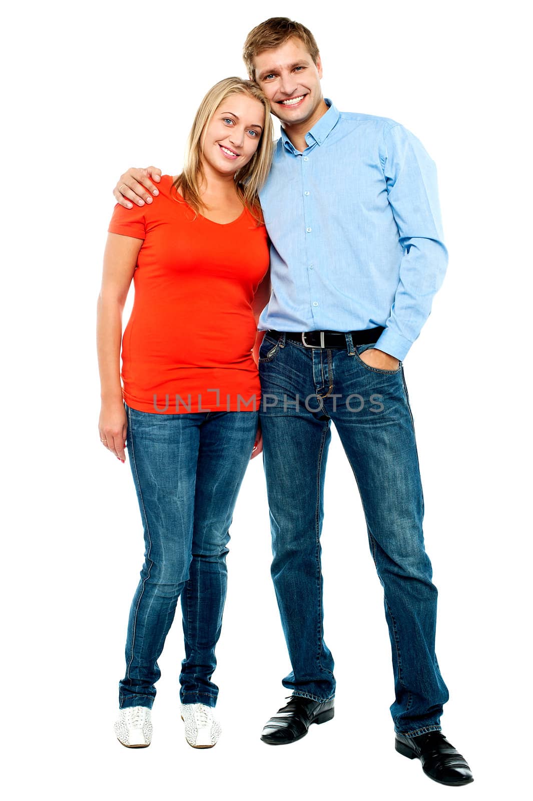 Portrait of happy young couple hugging at studio. Full length shot