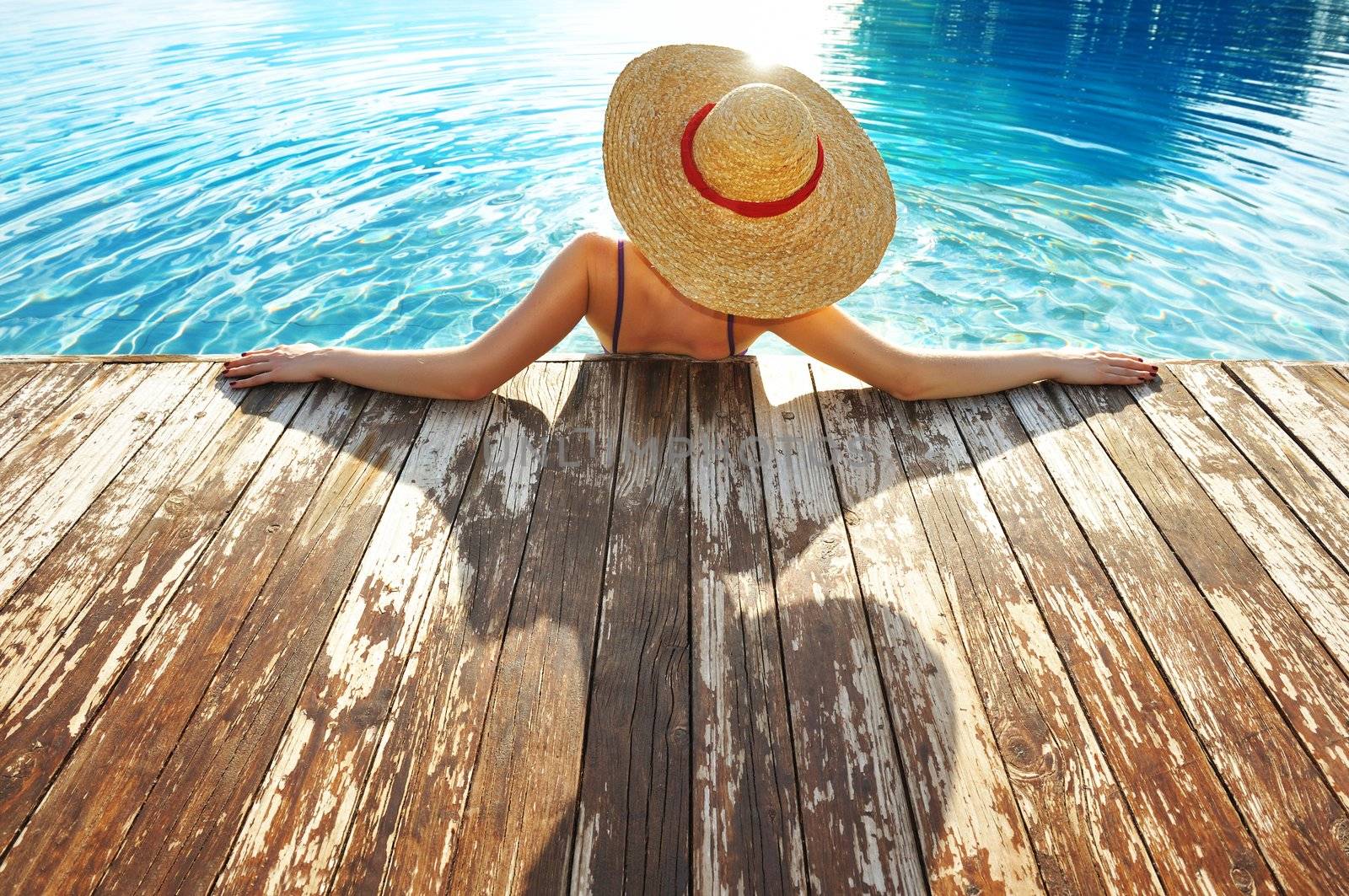 Woman in hat relaxing at the pool 