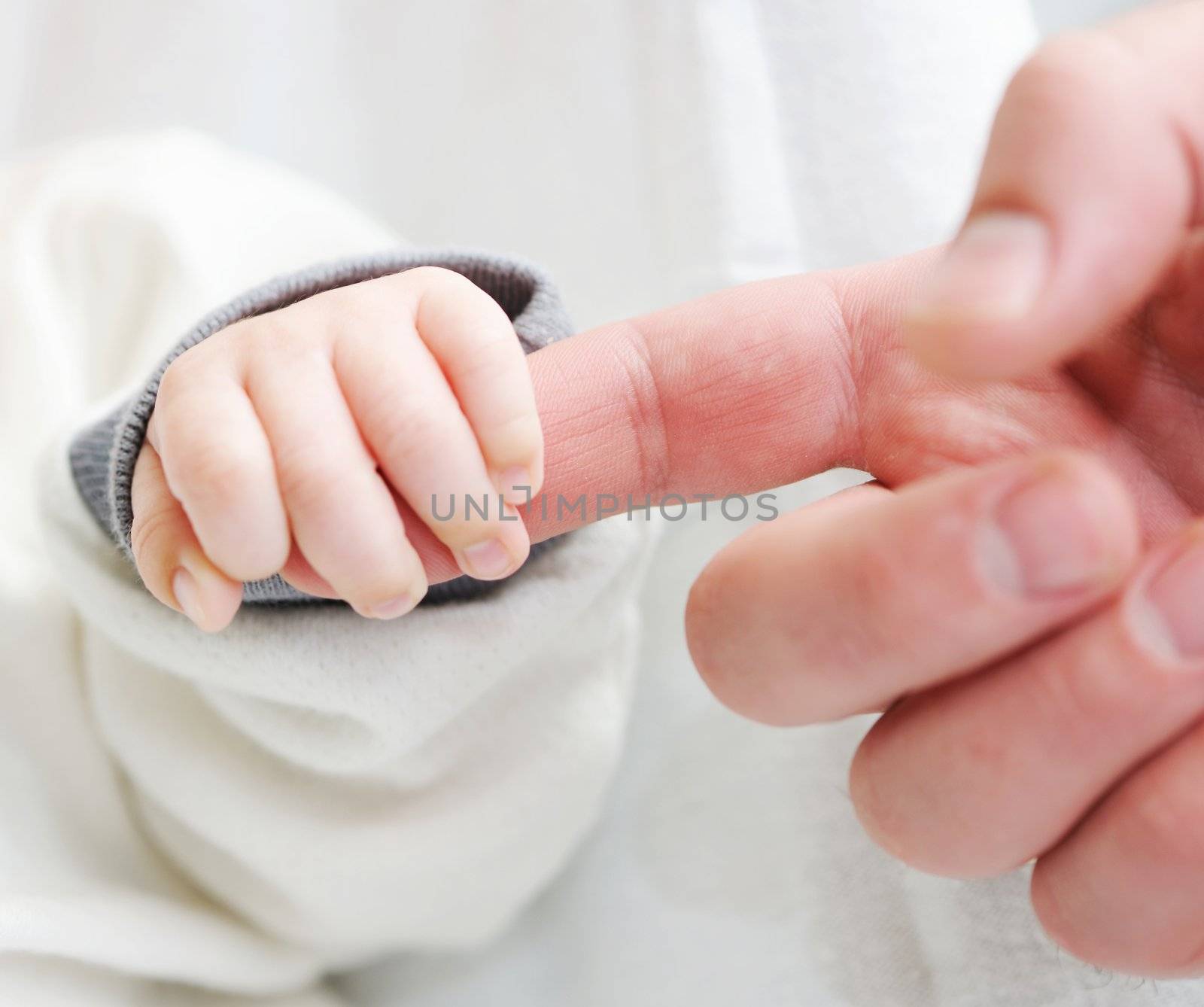 Newborn baby holding father's finger