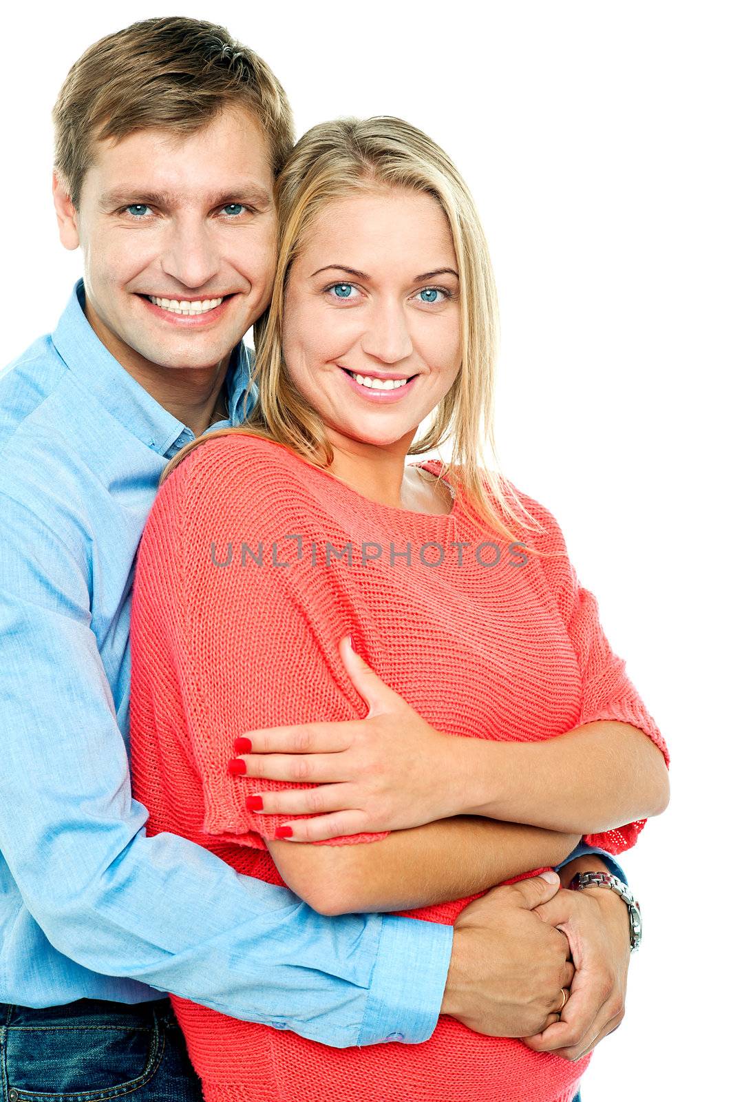 Charming lady posing with her hands crossed and her husband embracing from behind