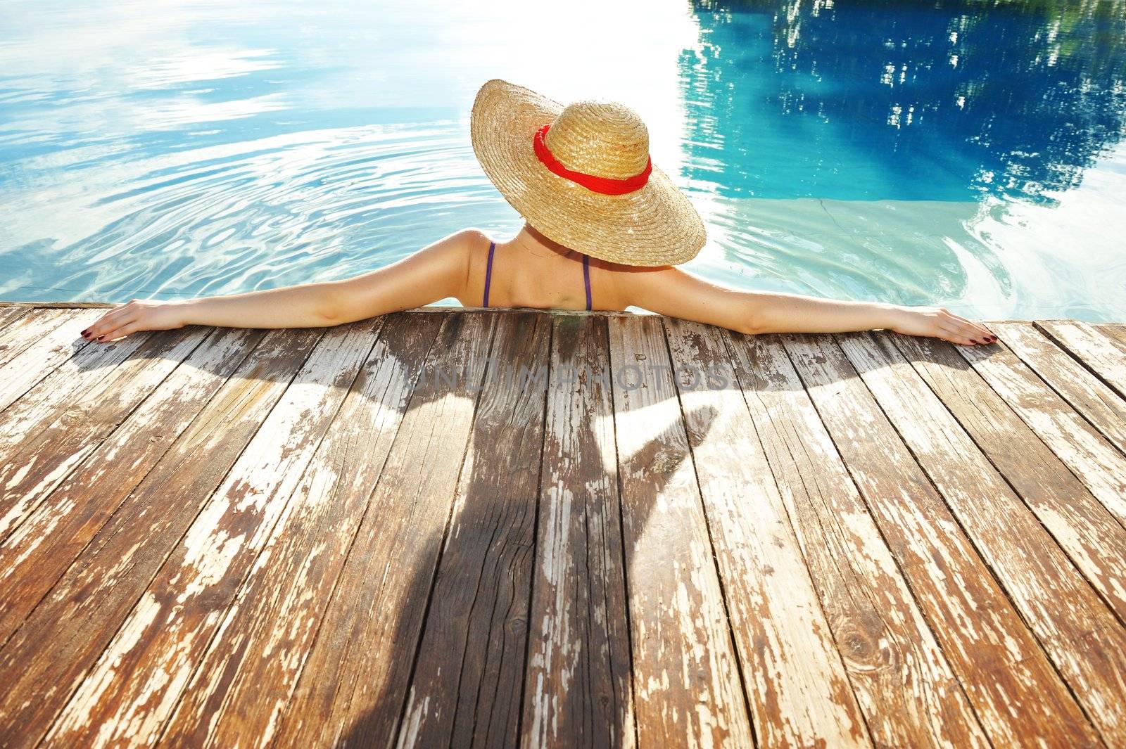 Woman in hat relaxing at the pool 