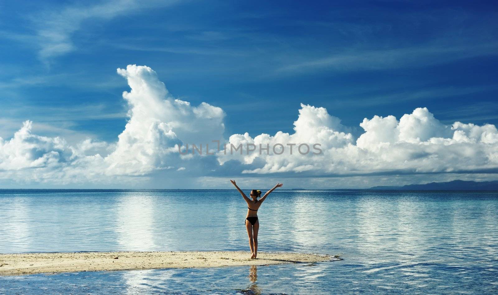 Girl on a tropical beach with outstretched arms