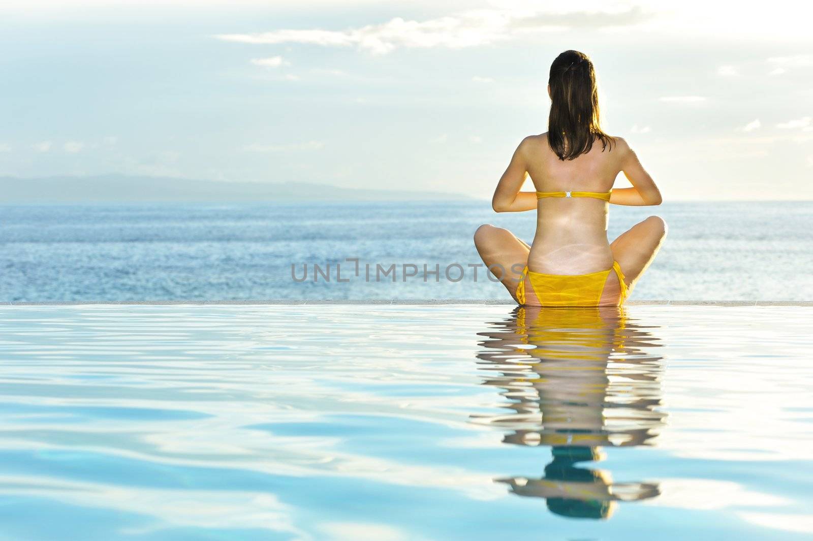Woman doing yoga at poolside by haveseen