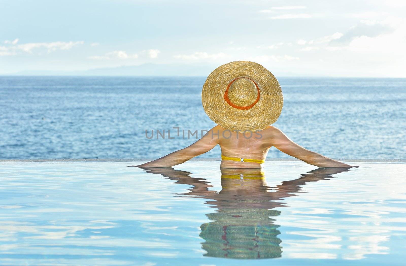 Woman in hat relaxing at the pool 
