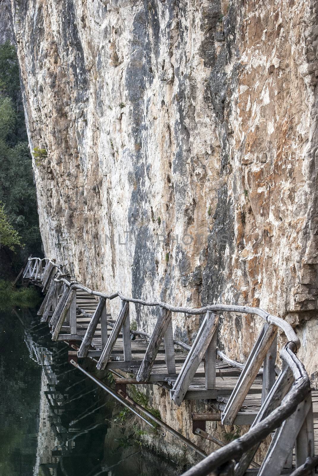 Rock vertical wall wooden path at river