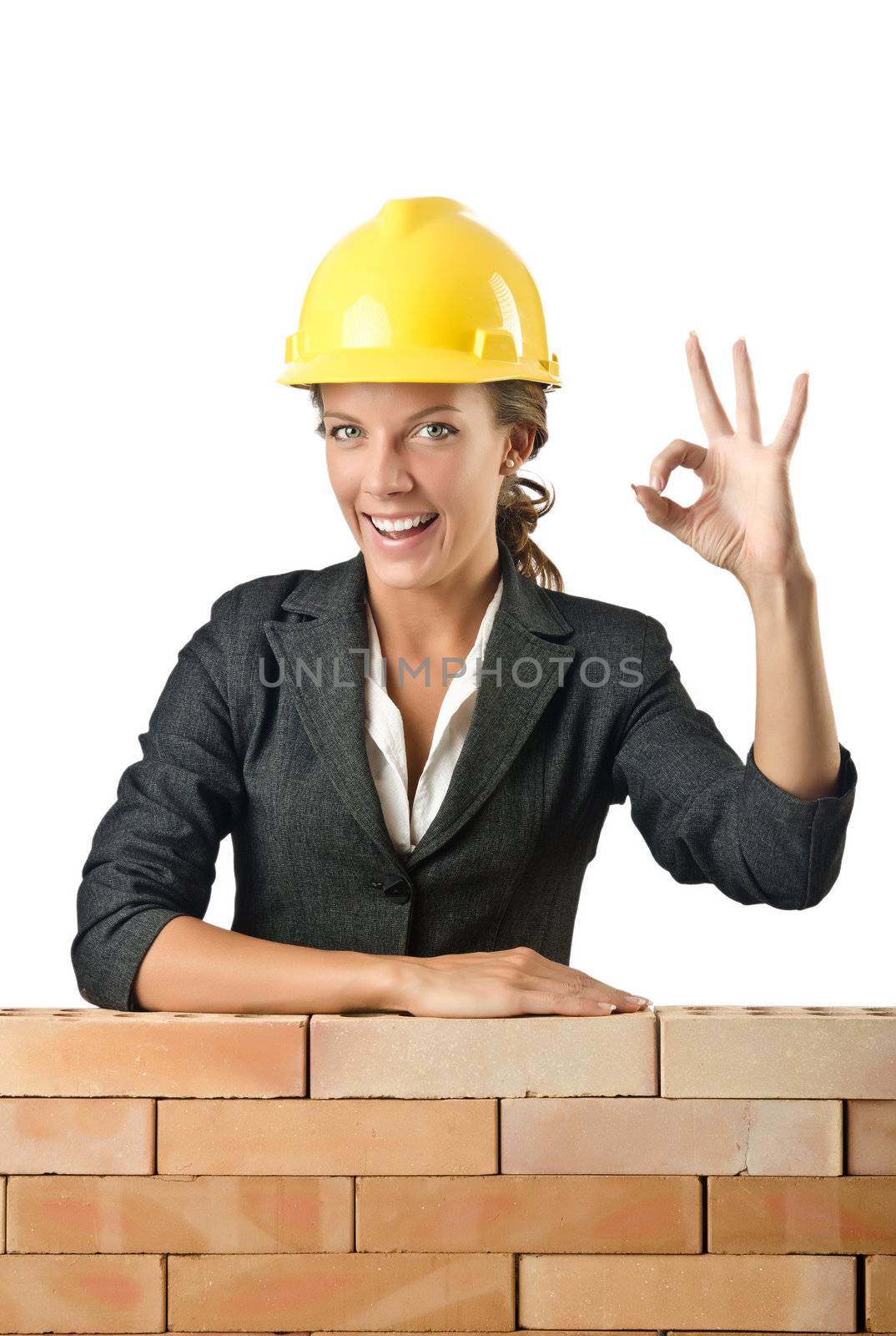 Young female builder near brick wall