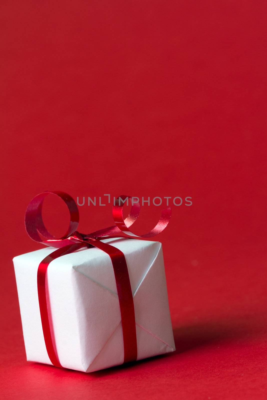 White gift box with red ribbon isolated on red color background