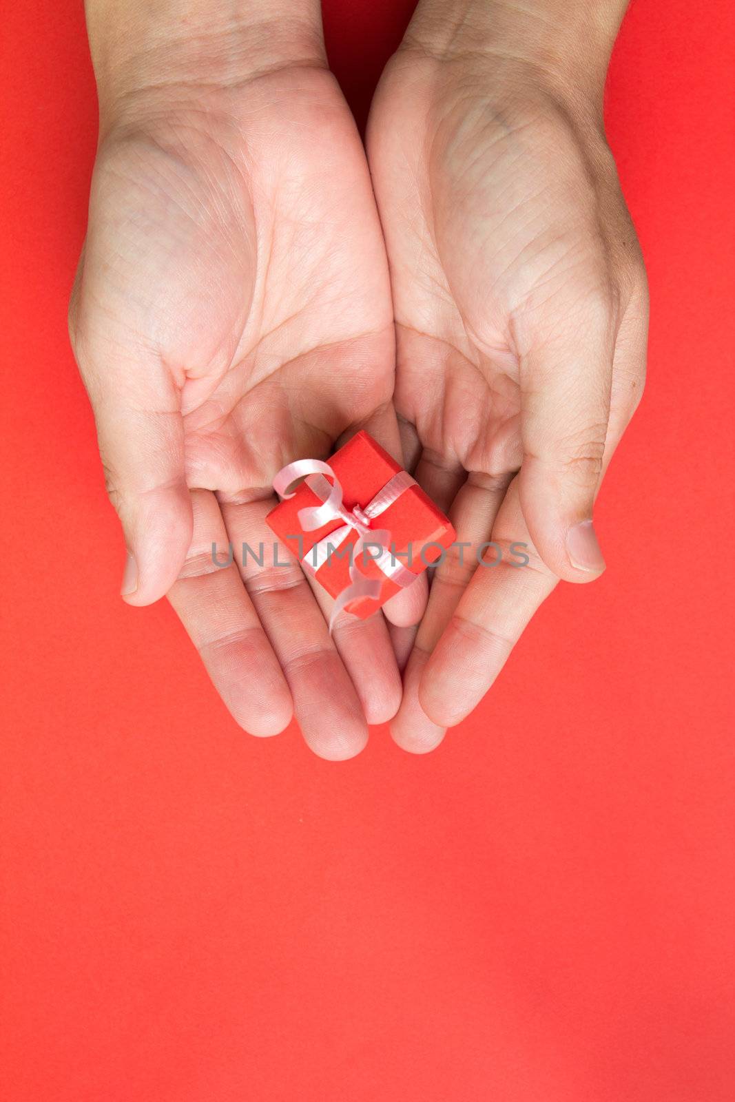 Red gift box with ribbon in hand isolated in red background