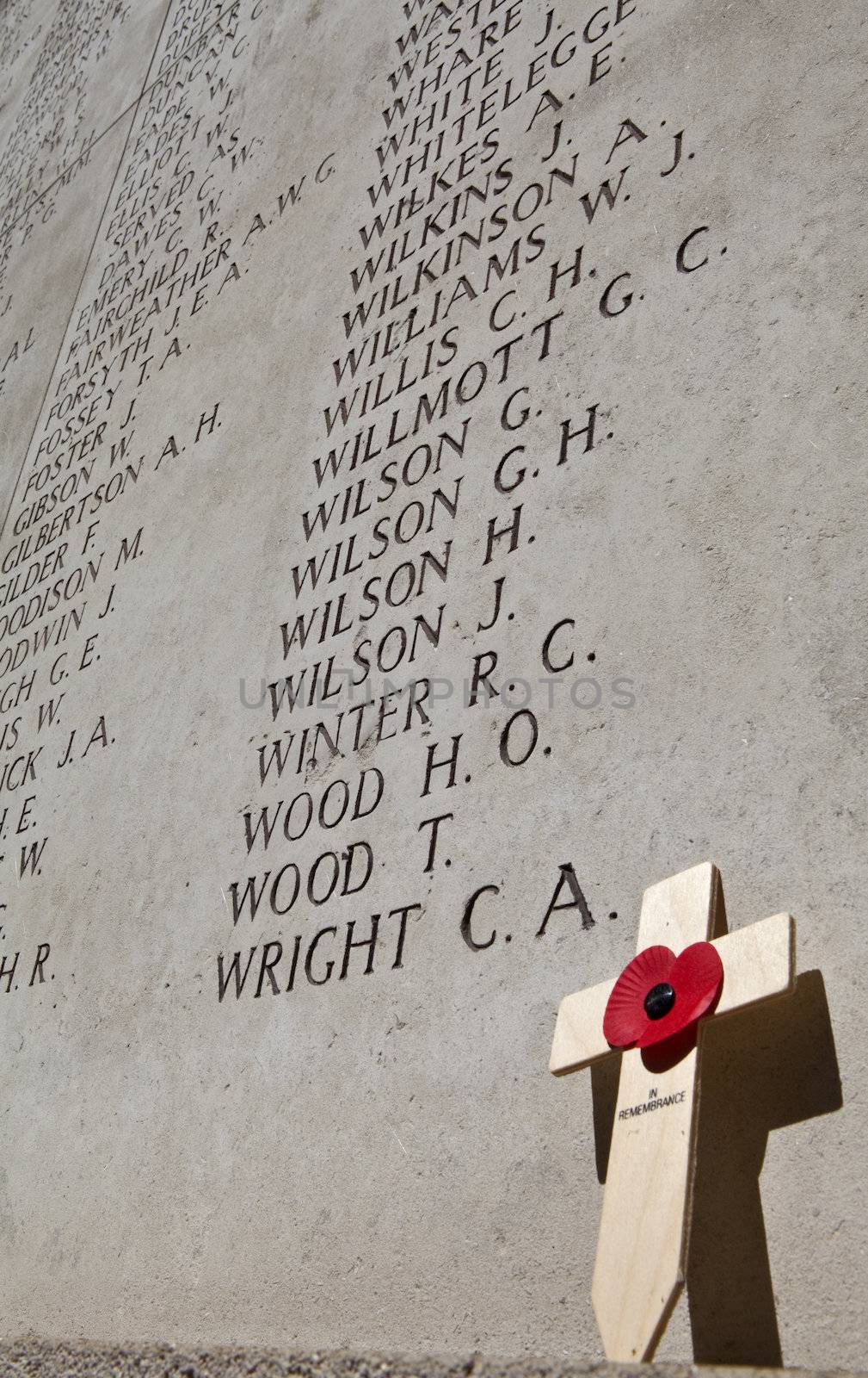 A Poppy, cross and names of fallen soldiers of the battle of Ypres.  The Menin Gate is dedicated to the  British and Commonwealth soldiers who were killed in the Ypres Salient of World War 1 and whose graves are unknown. 