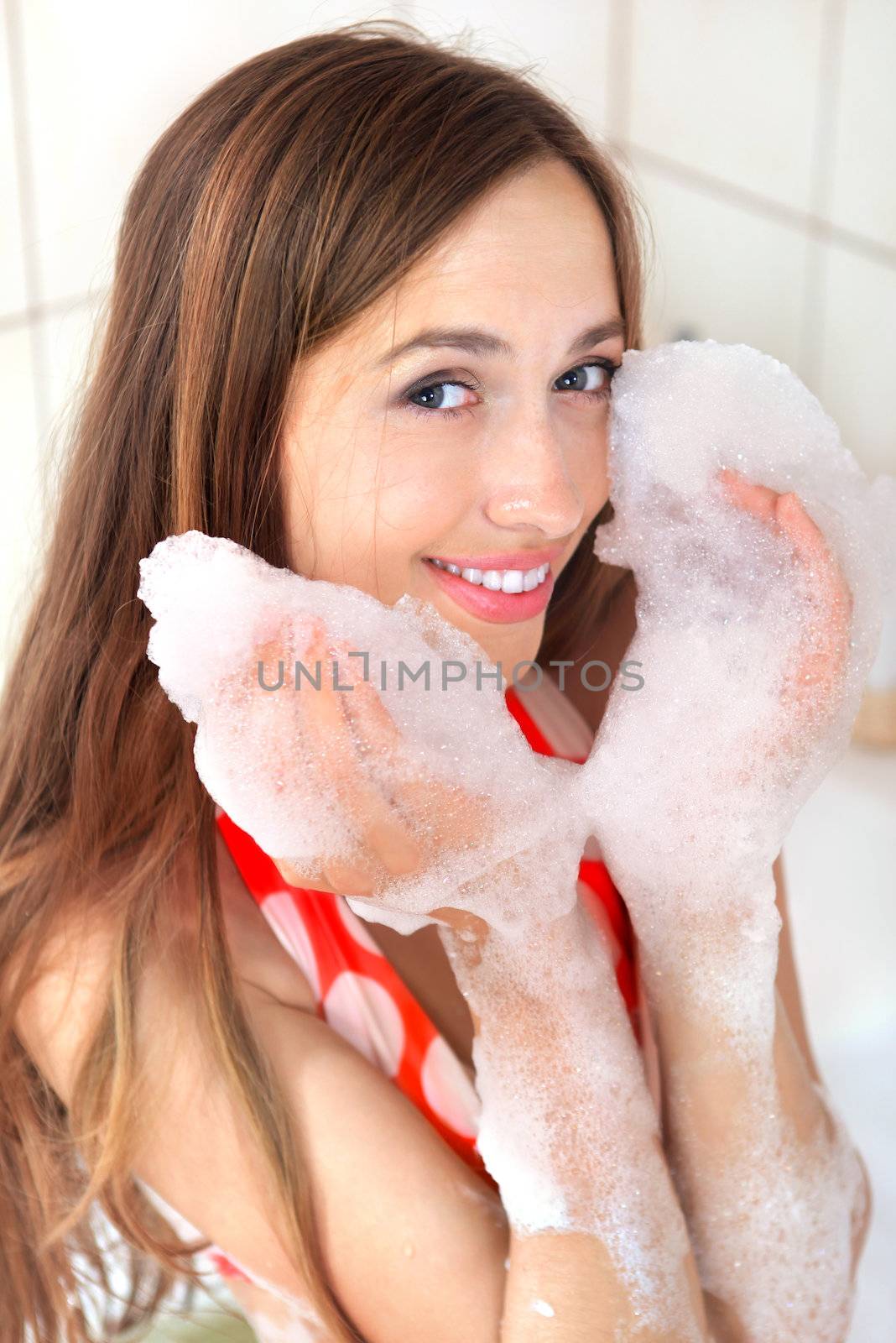 young happy girl with foam on hands in bathroom