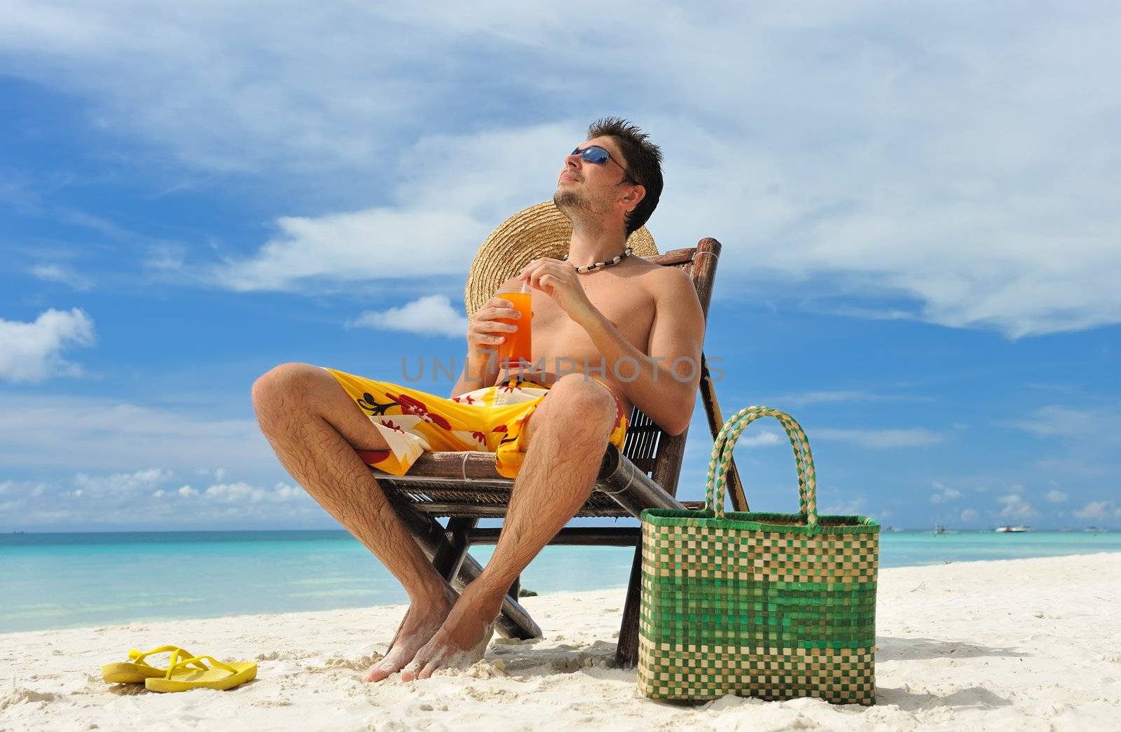 Man on a tropical beach with cocktail