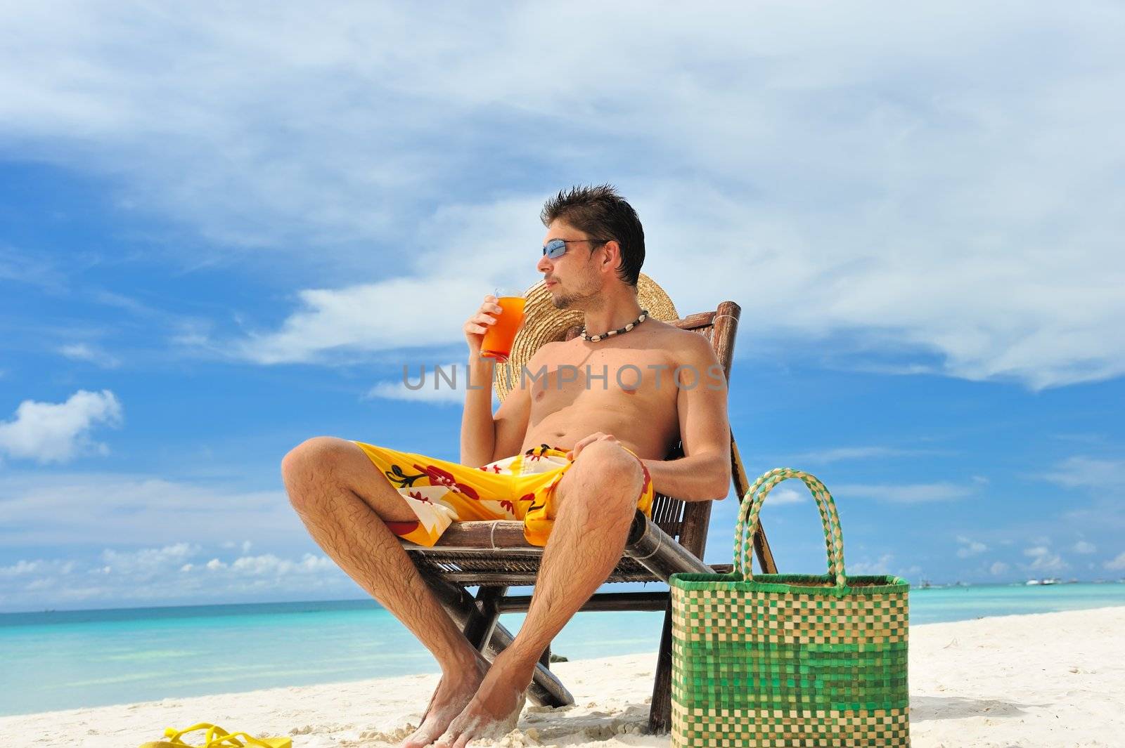 Man on a tropical beach with cocktail