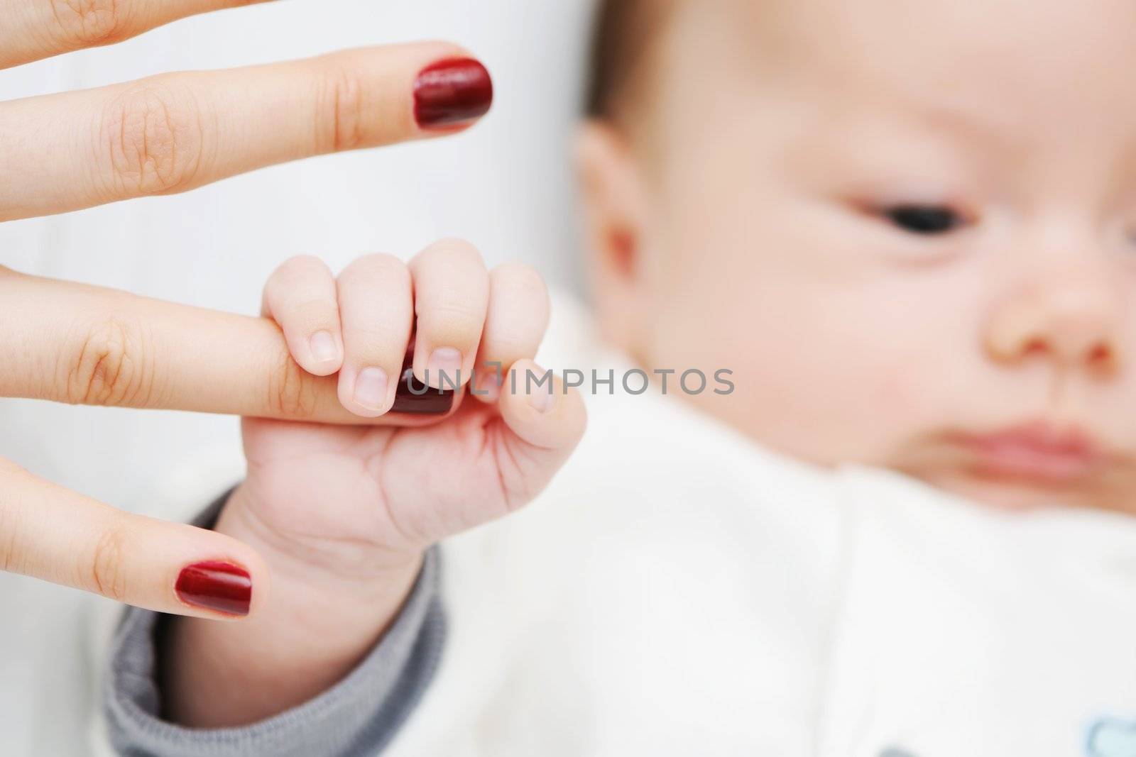 Newborn baby holding mother's finger
