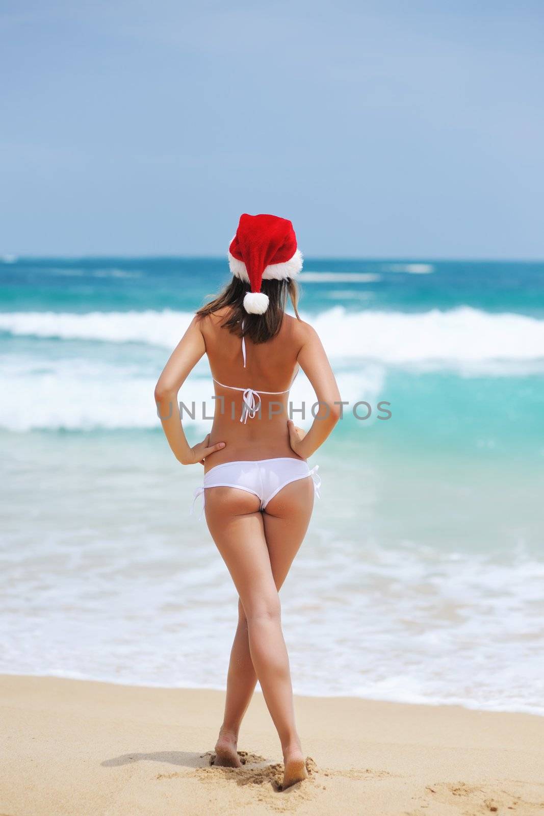 Woman on the beach in santa's hat