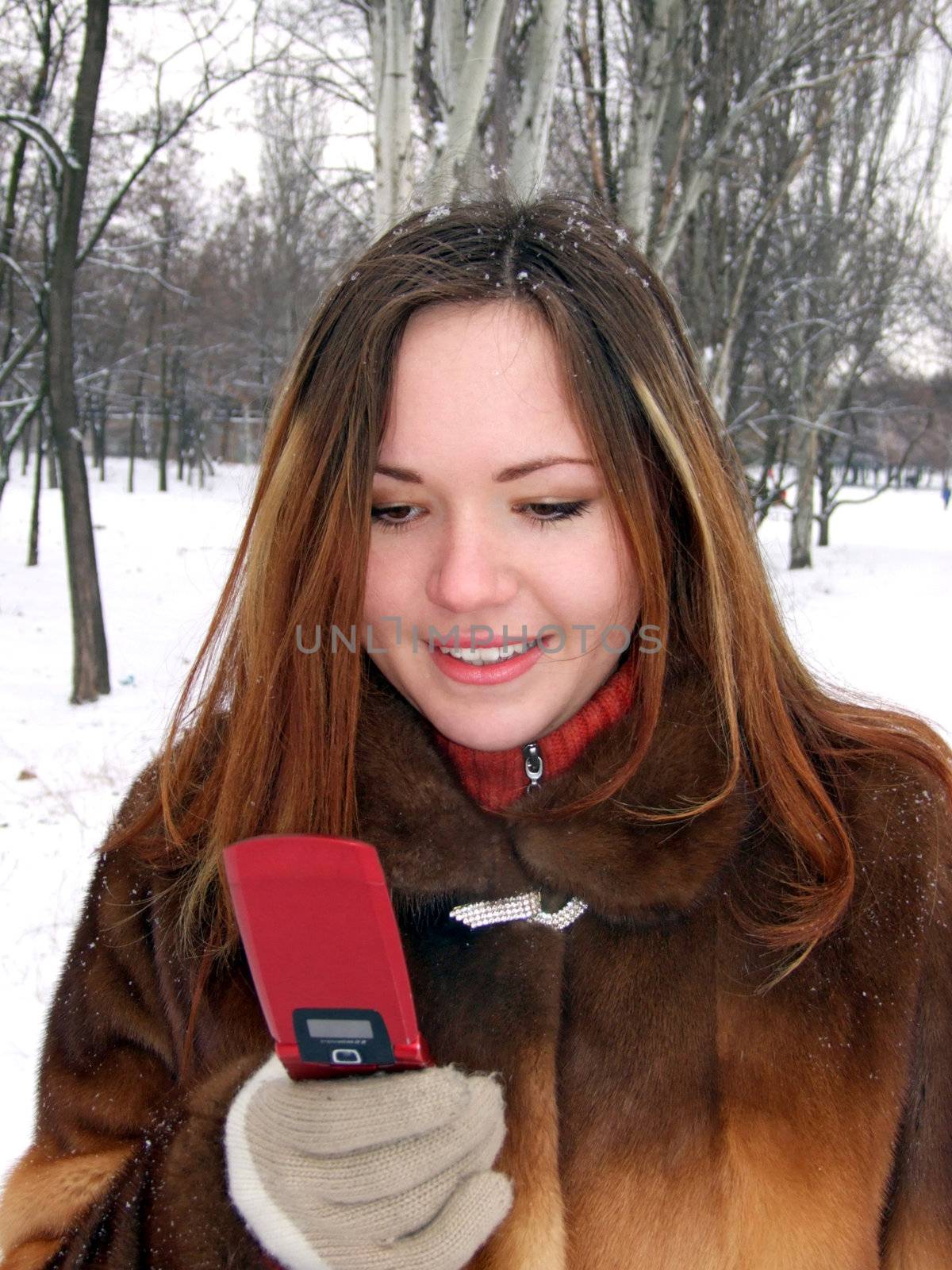The girl in the winter in park with phone in a hand