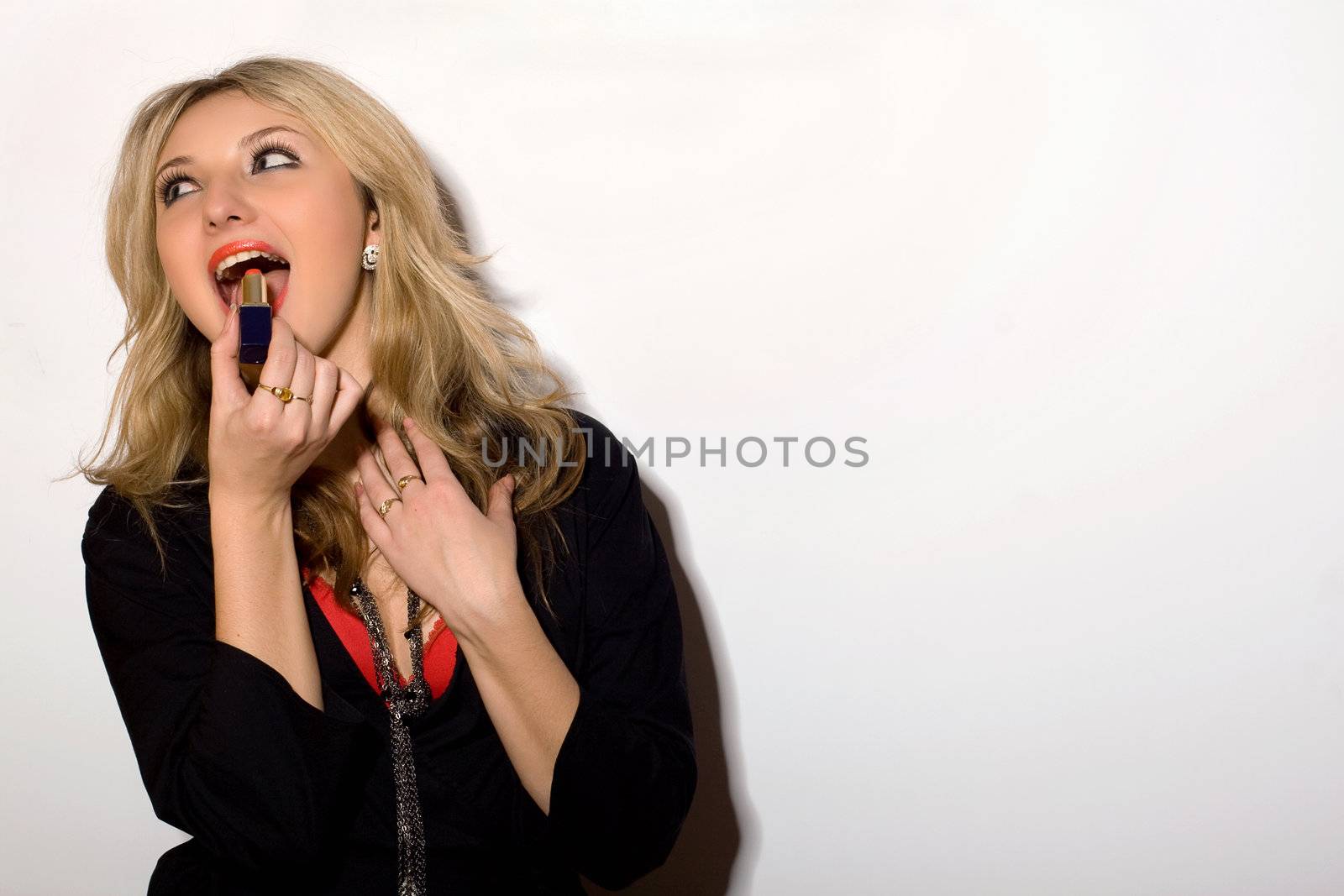 Cheerful young blond woman with lipstick in hand