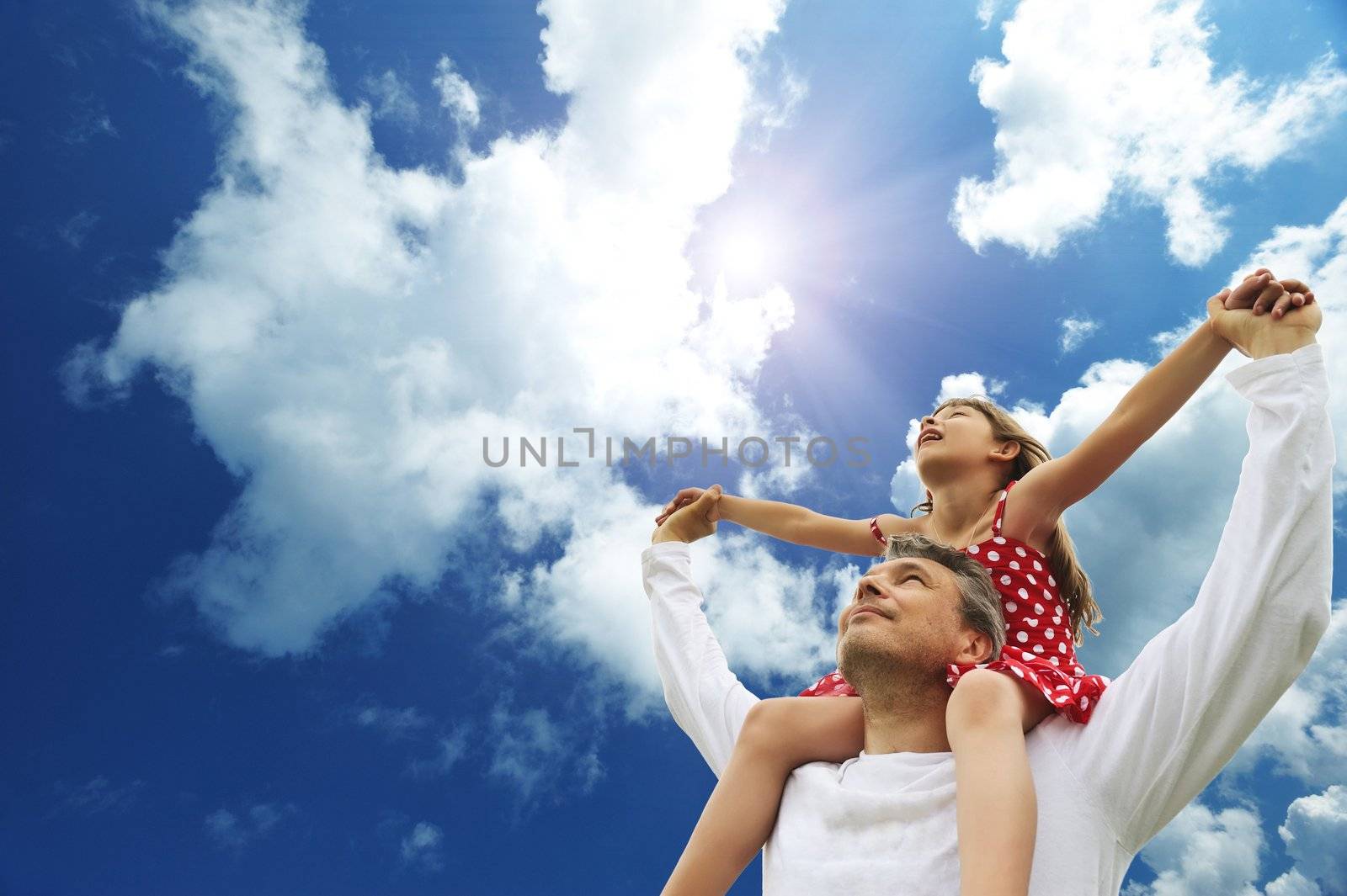 Father and daughter against sky 