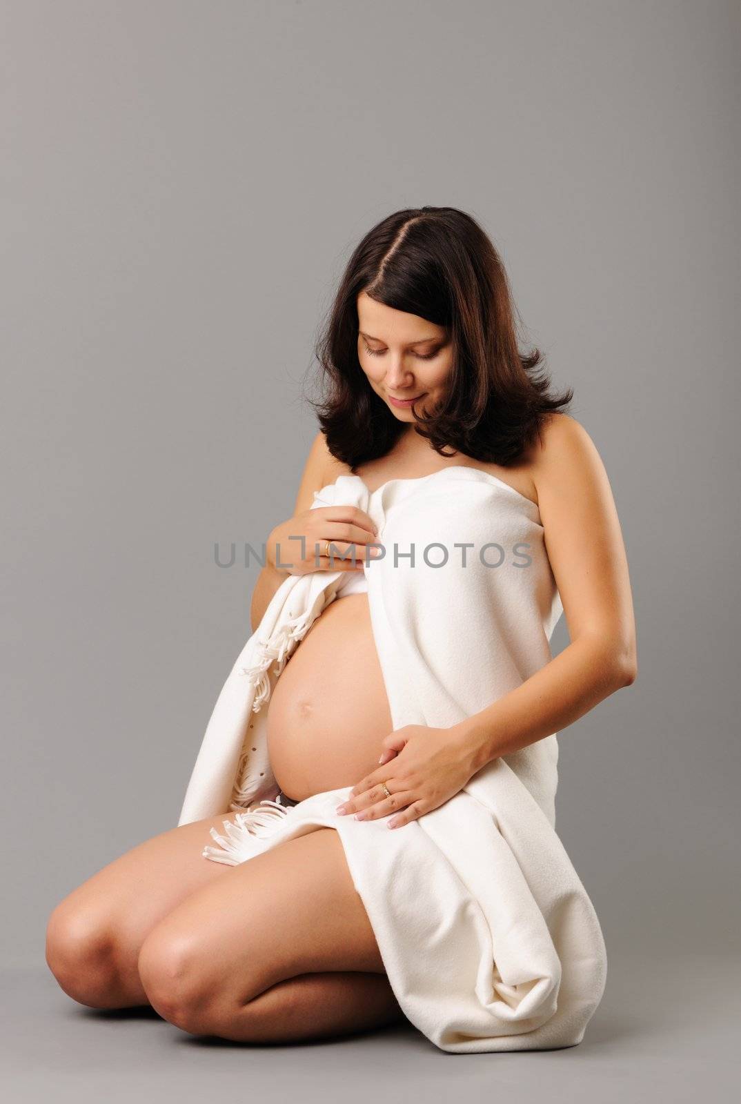 Portrait of a sitting pregnant woman looking at her belly
