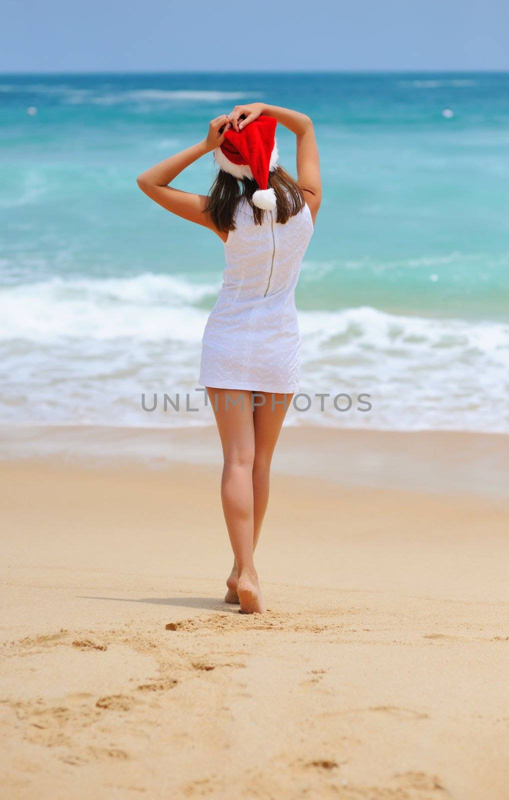 Woman on the beach in santa's hat