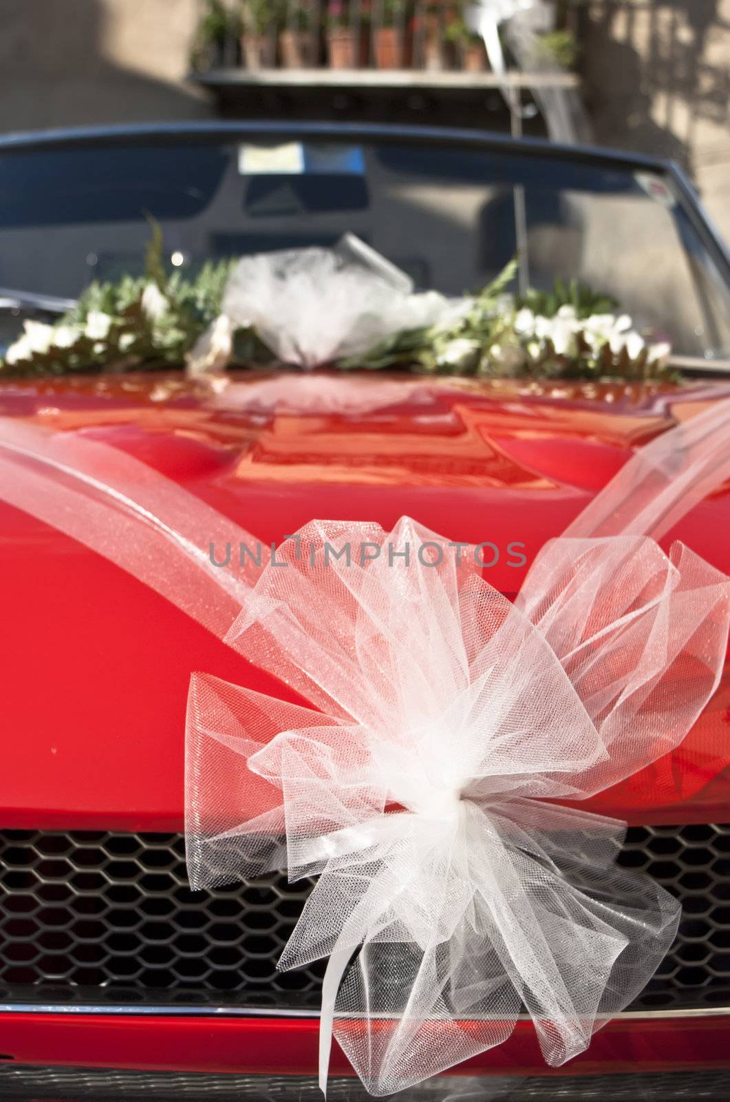 Red wedding car with white ribbon and flowers on the windshield