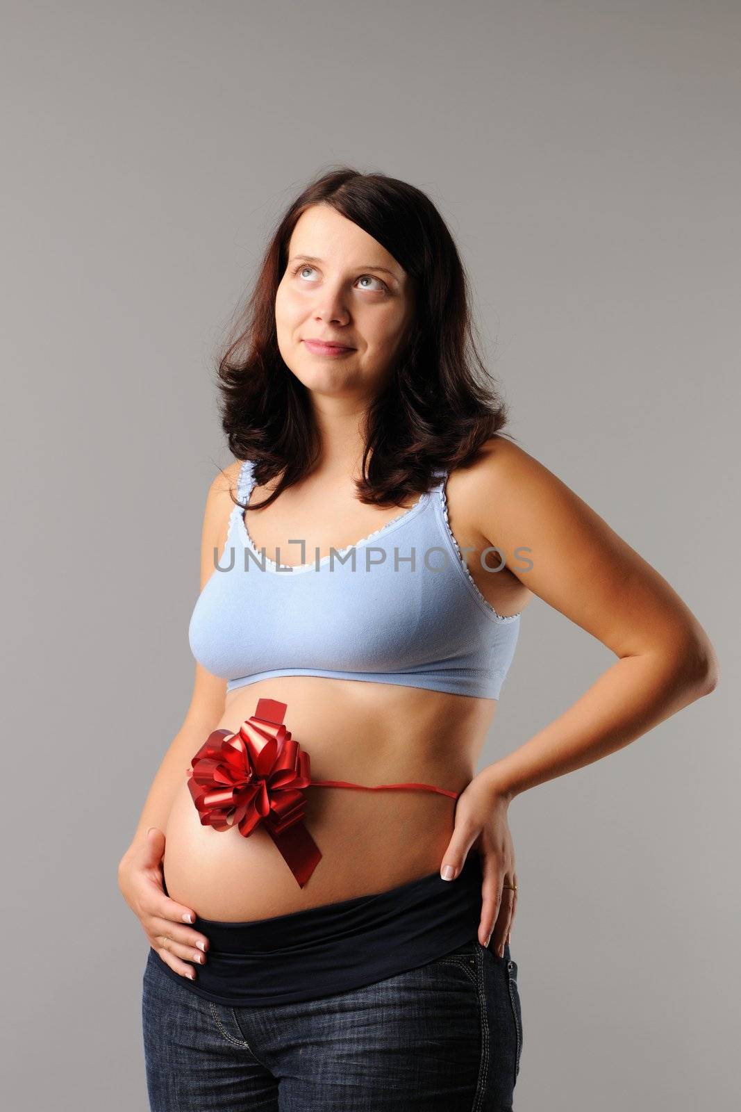 Portrait of a pregnant woman with wrapping bow on her her belly
