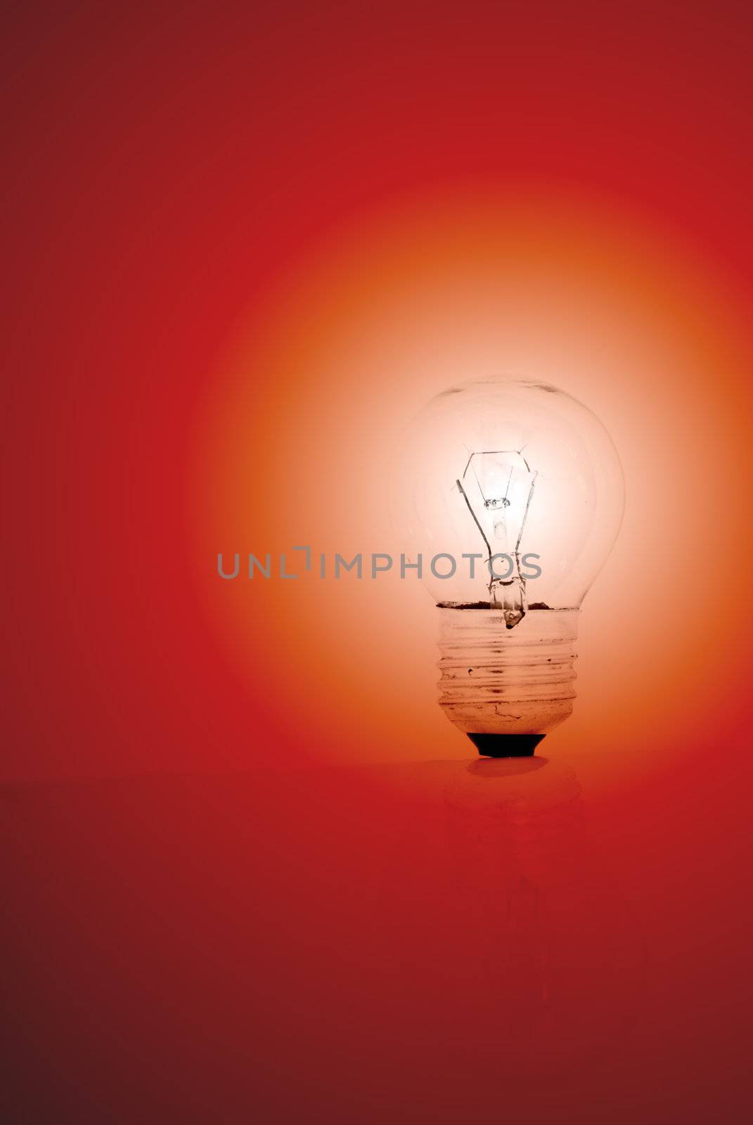 A lit light bulb on a red background.