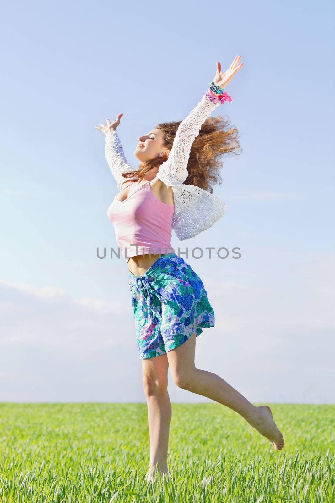 Happy beautiful young woman in a green field