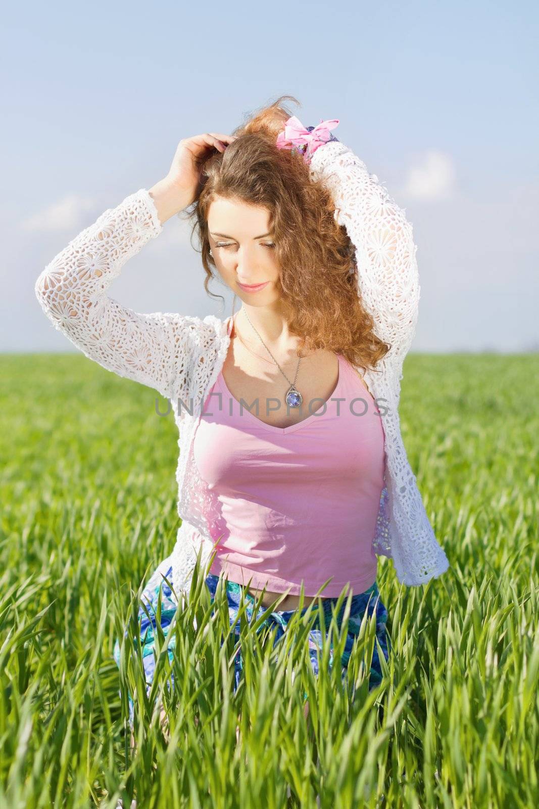 Portrait of charming young woman in a green field