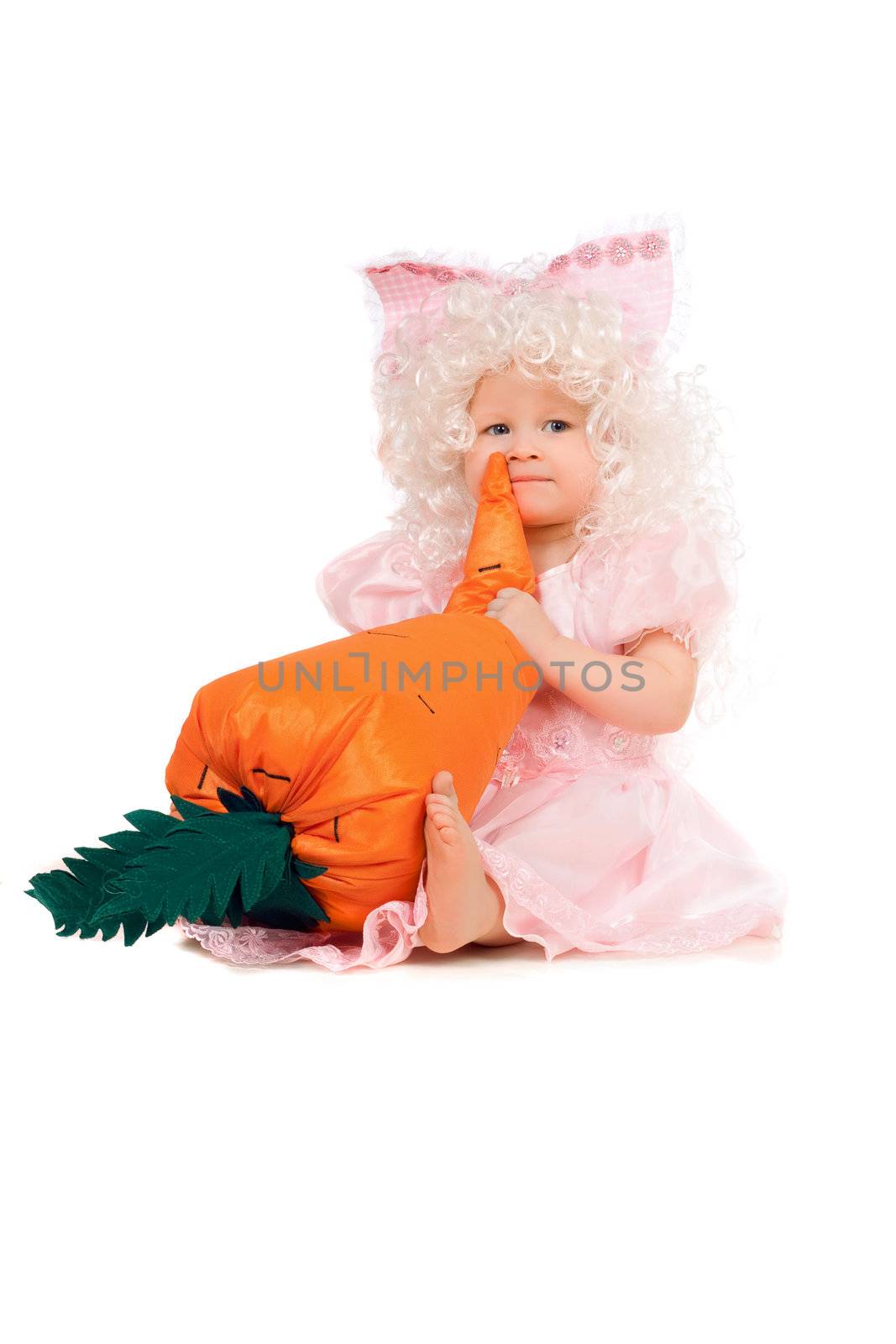 Baby girl plays with a carrot. Isolated on white