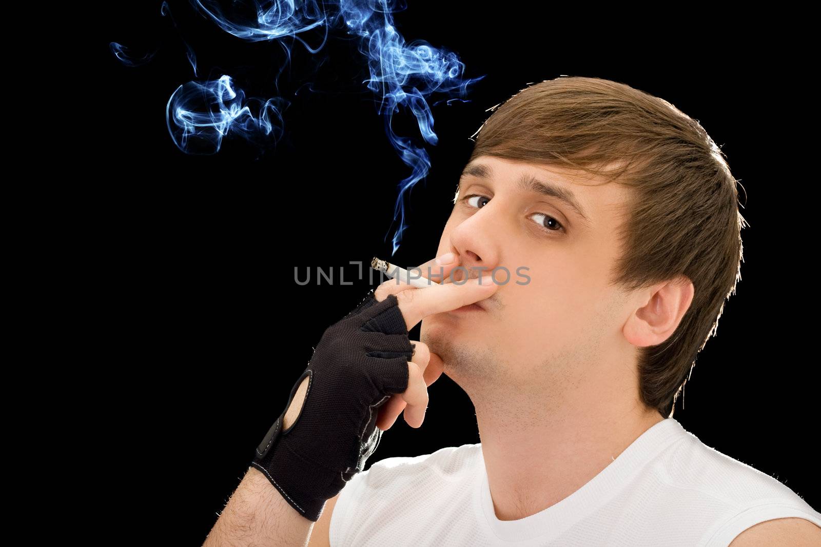 Young man smoking a cigarette. Isolated on black