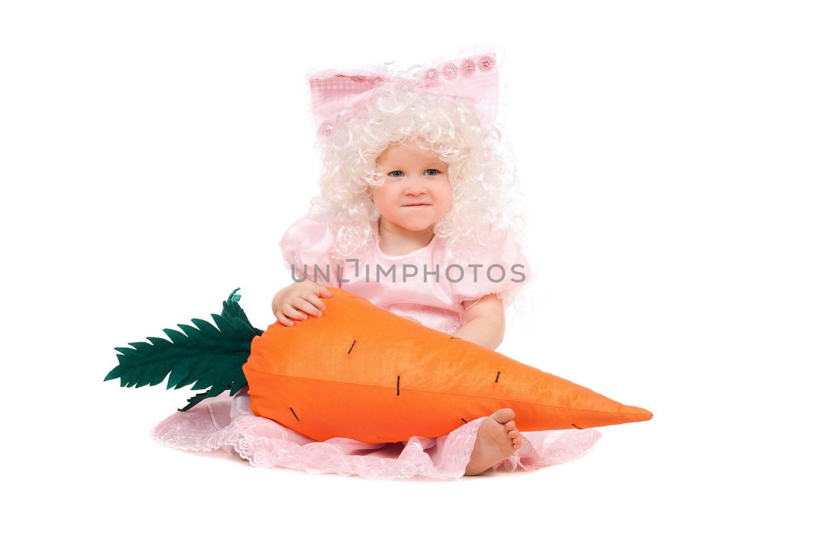 Funny baby girl plays with a carrot. Isolated