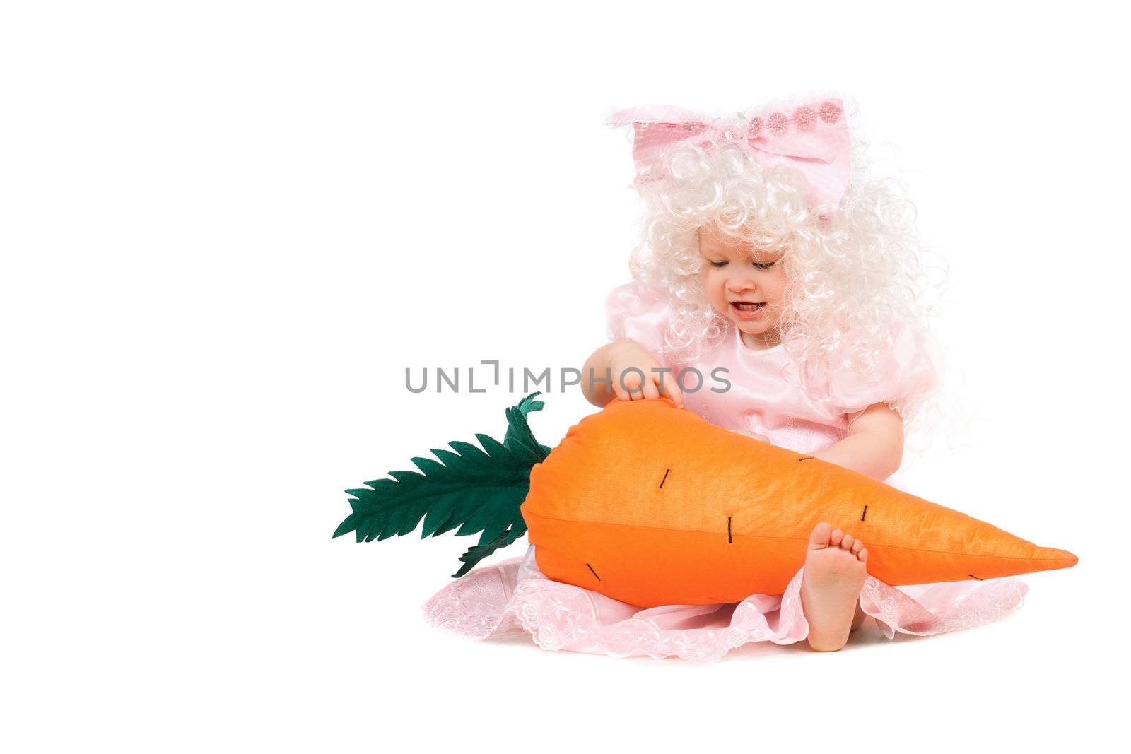 Funny baby girl plays with a carrot