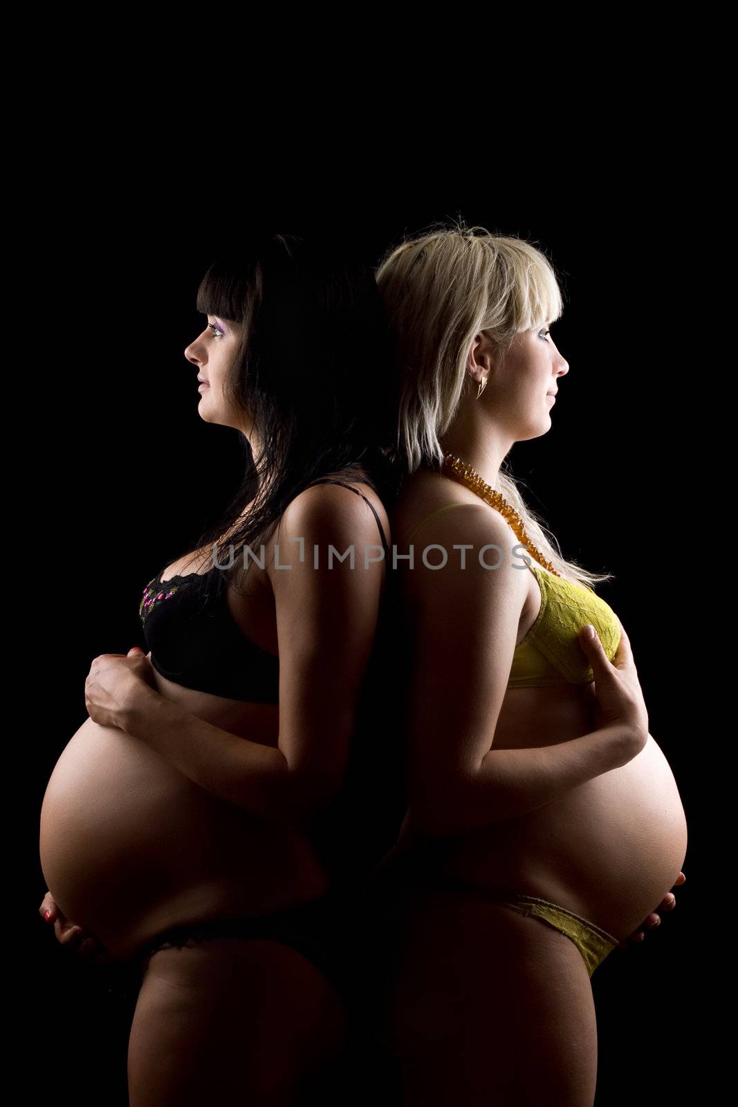 Pregnant blonde and brunette. Isolated on black