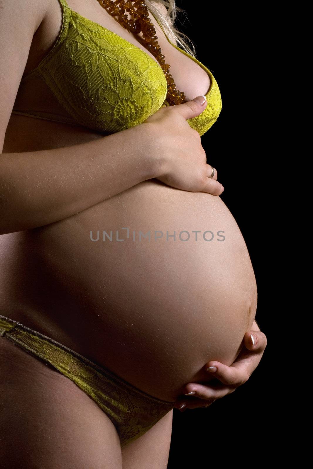 Belly of a pregnant young woman. Isolated on black