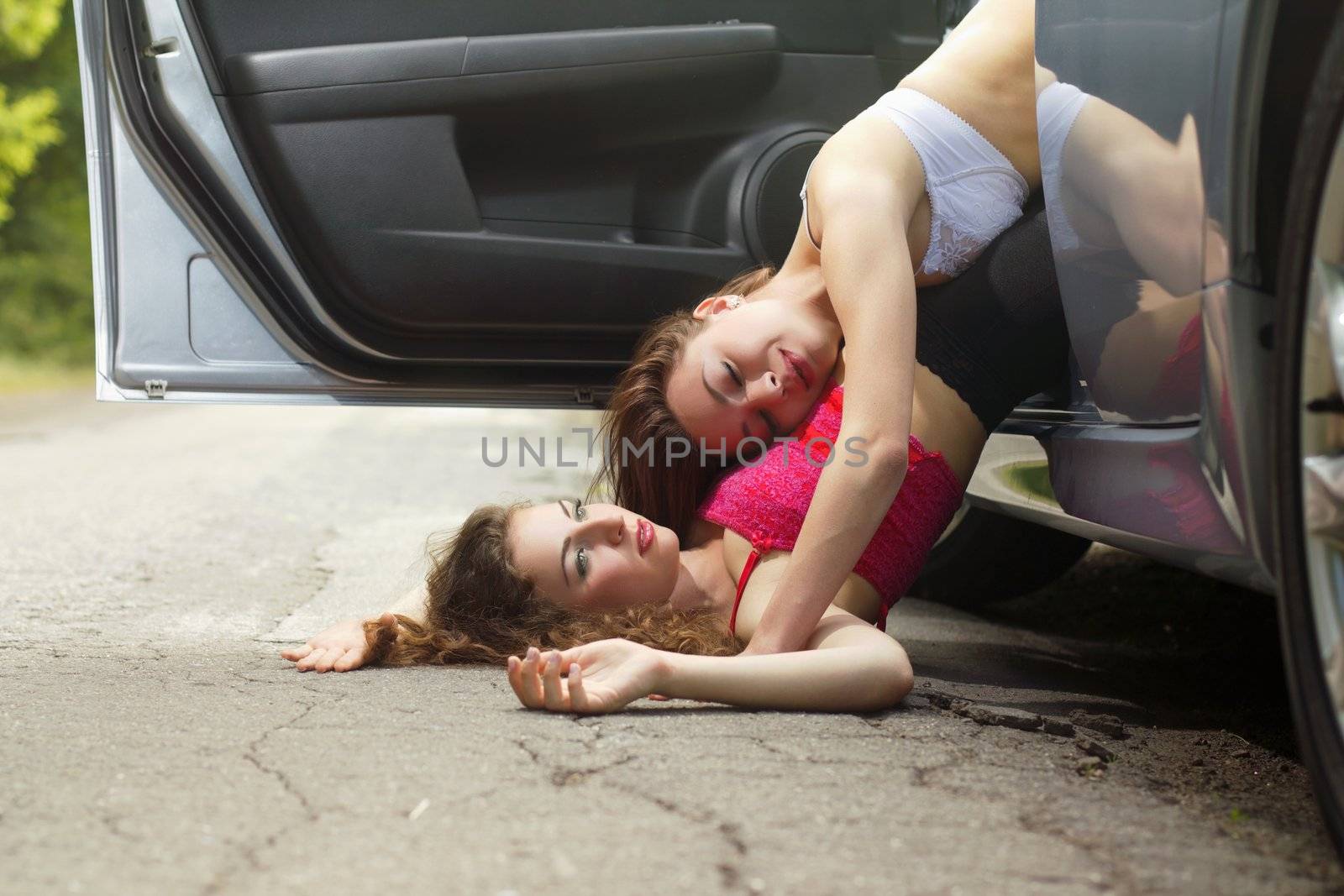 Two cute sexy young women lying on the road