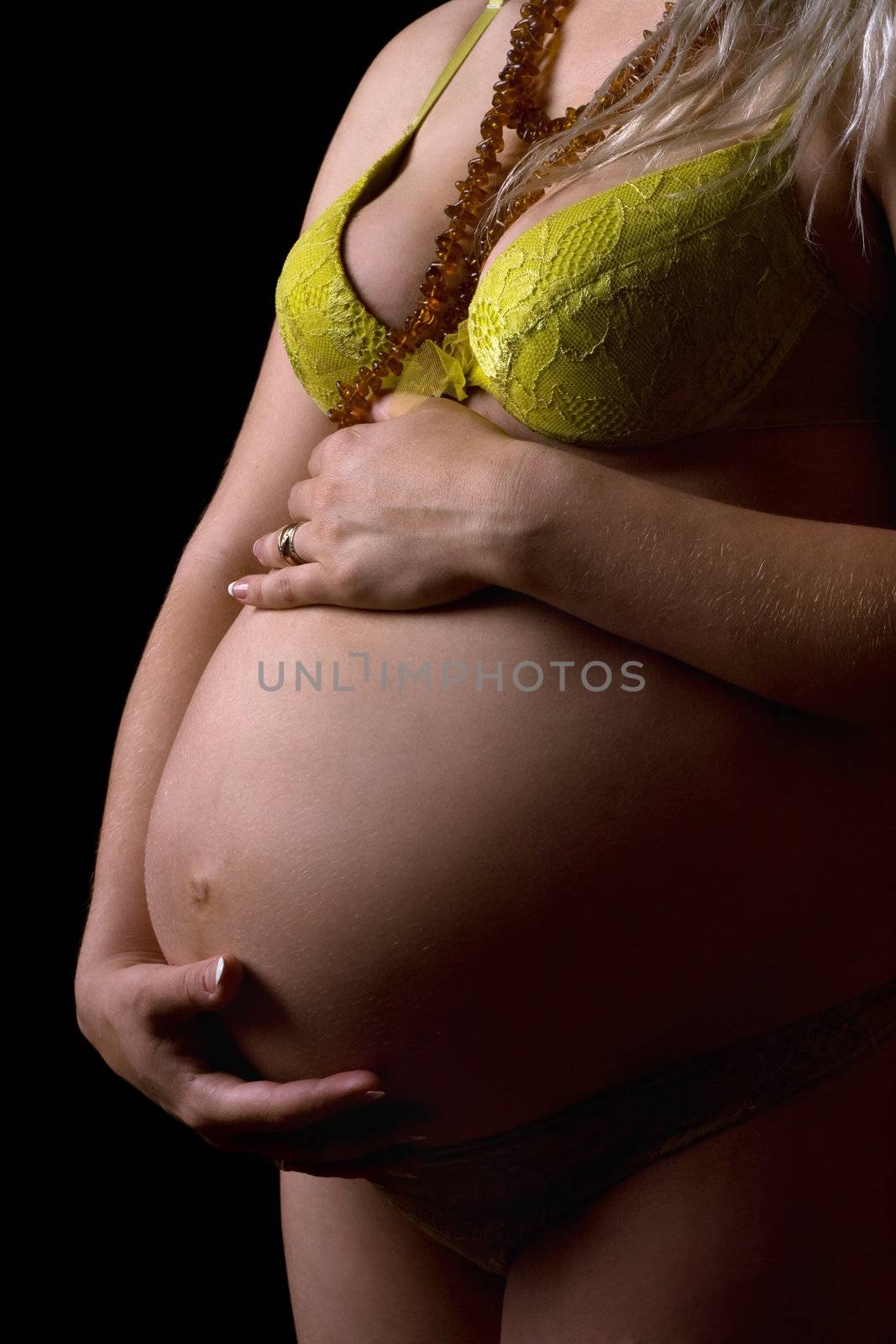 Belly of a young pregnant woman. Isolated on black