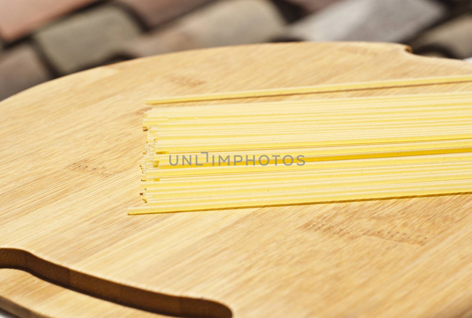 spaghetti pasta on wooden board with roof in the background.