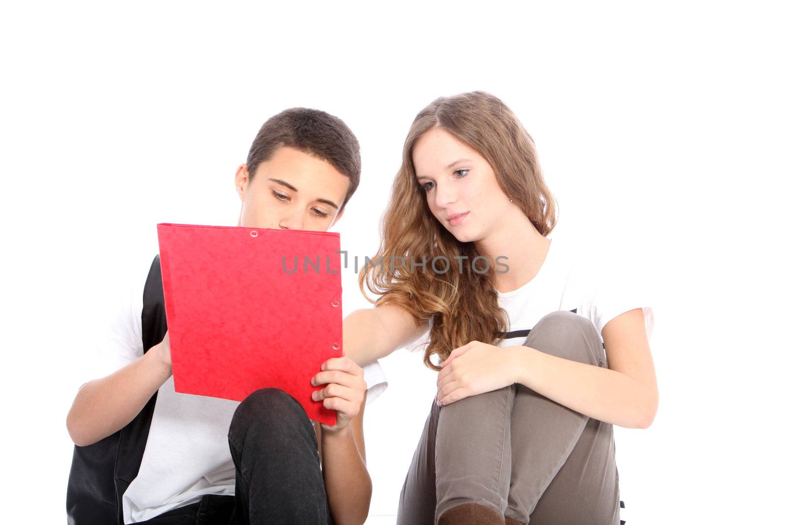 Two young teenage students sitting on the floor working together on a project isolated on white