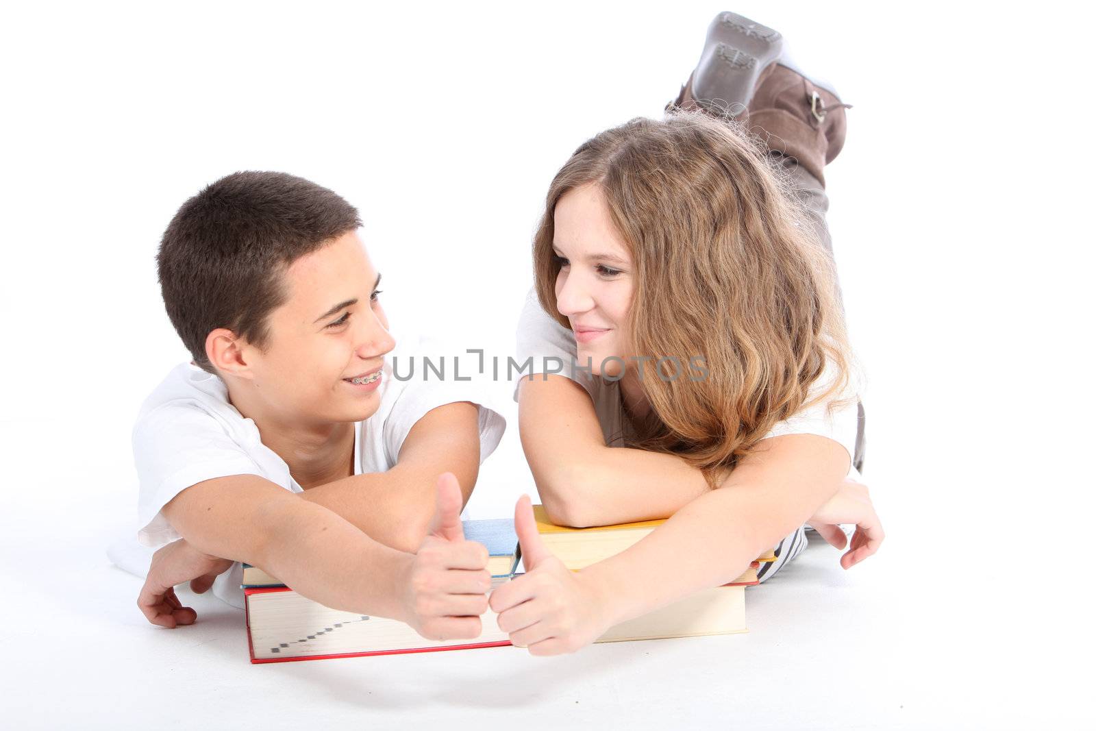 Teenage boy and girl with books giving thumbs up gesture isolated on white in studio