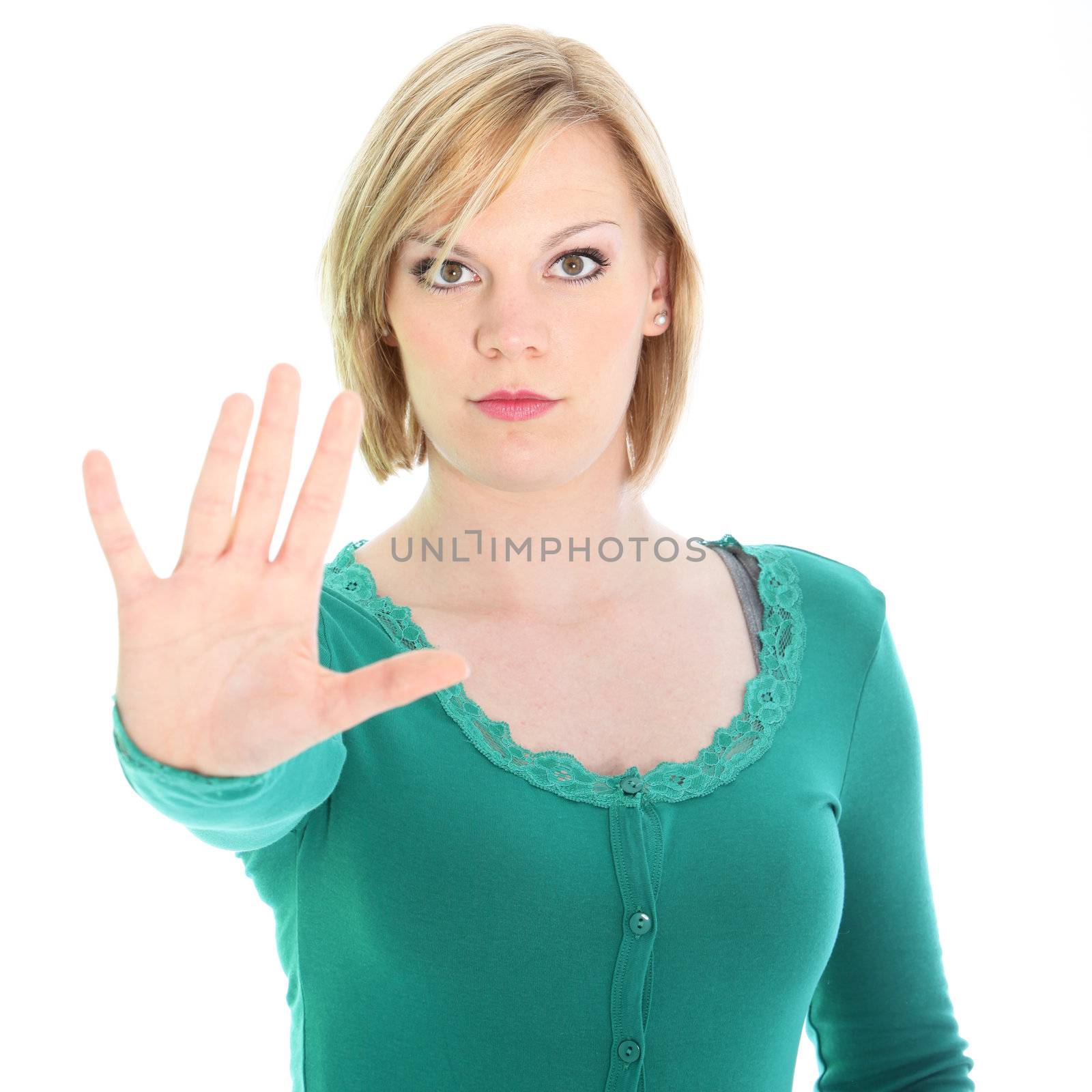 Resolute woman with a determined expression calling a halt with her hand holding it at arms length with fingers splayed isolated on white