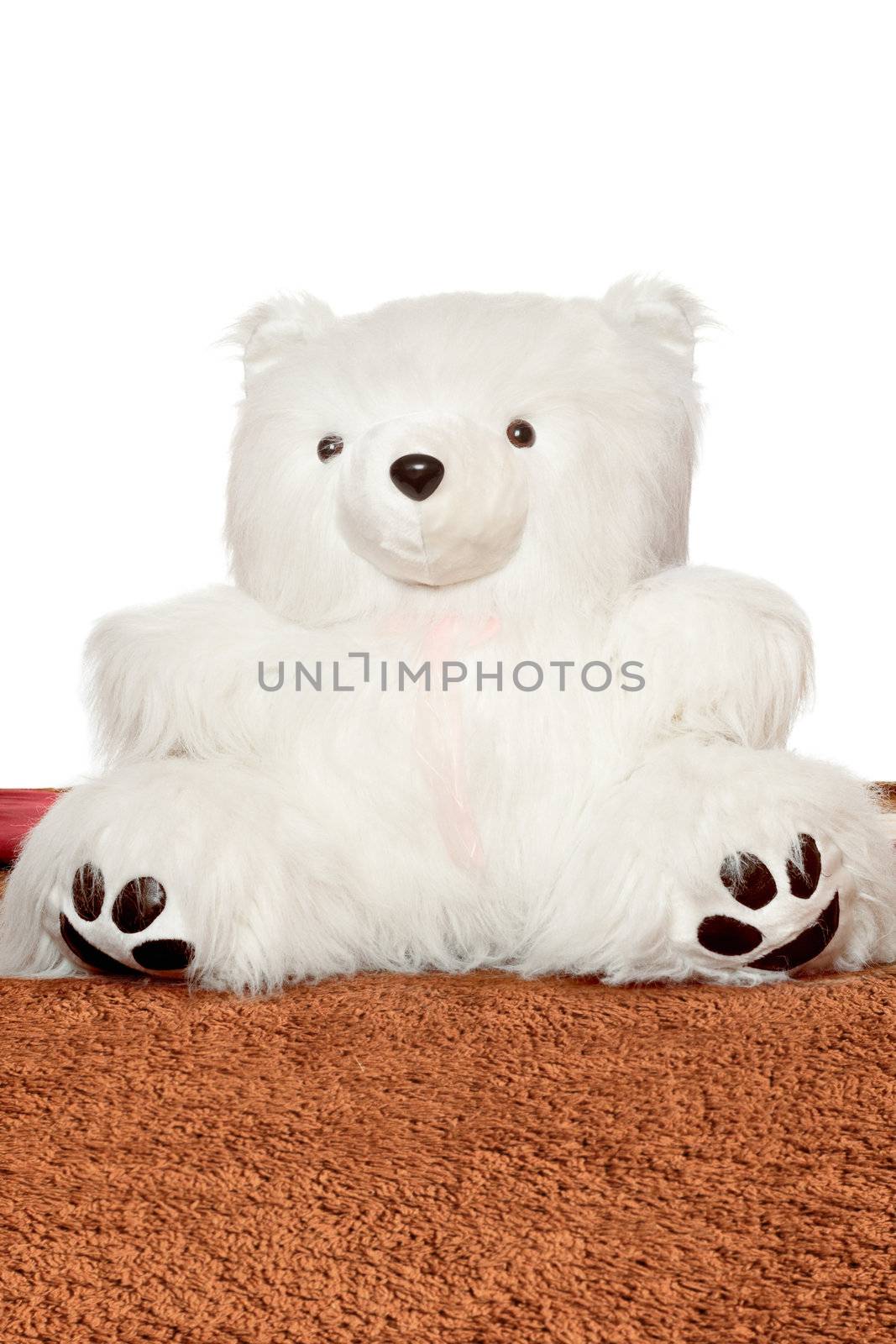 Big white teddy bear sitting on a brown blanket