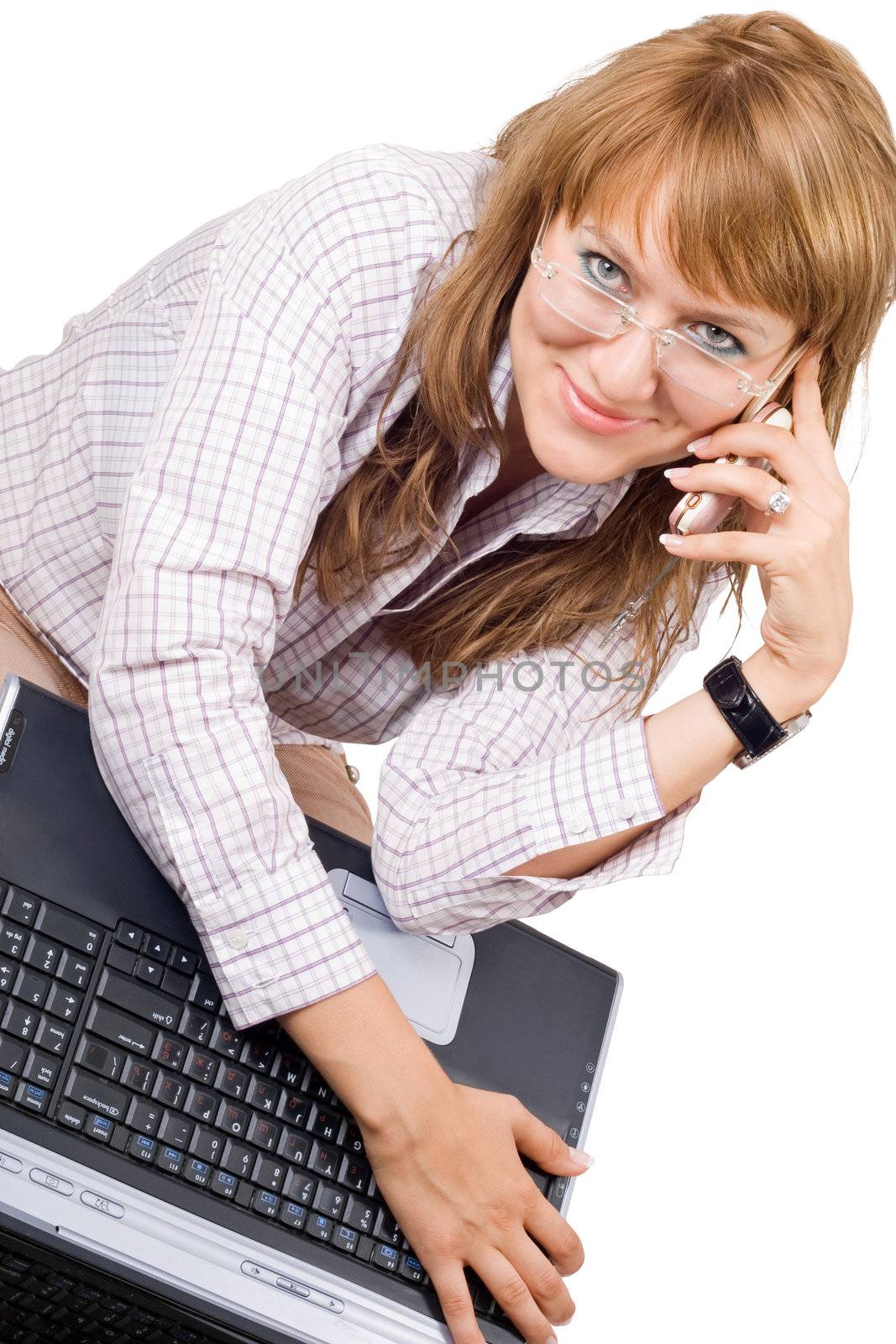 The smiling young woman sits with the laptop and phone. Isolated