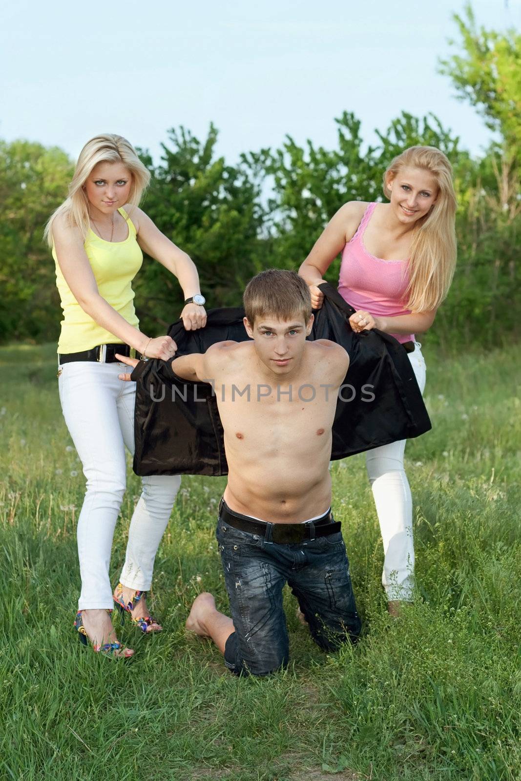 Two playful blonde and young man outdoors. Focus on guy