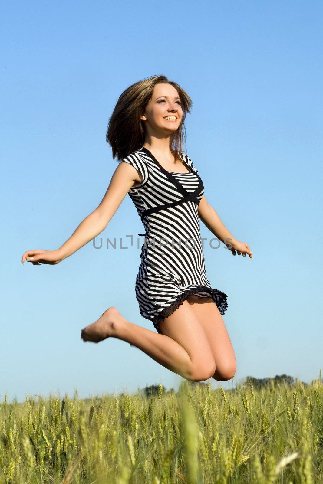 Happy pretty girl jumping in field