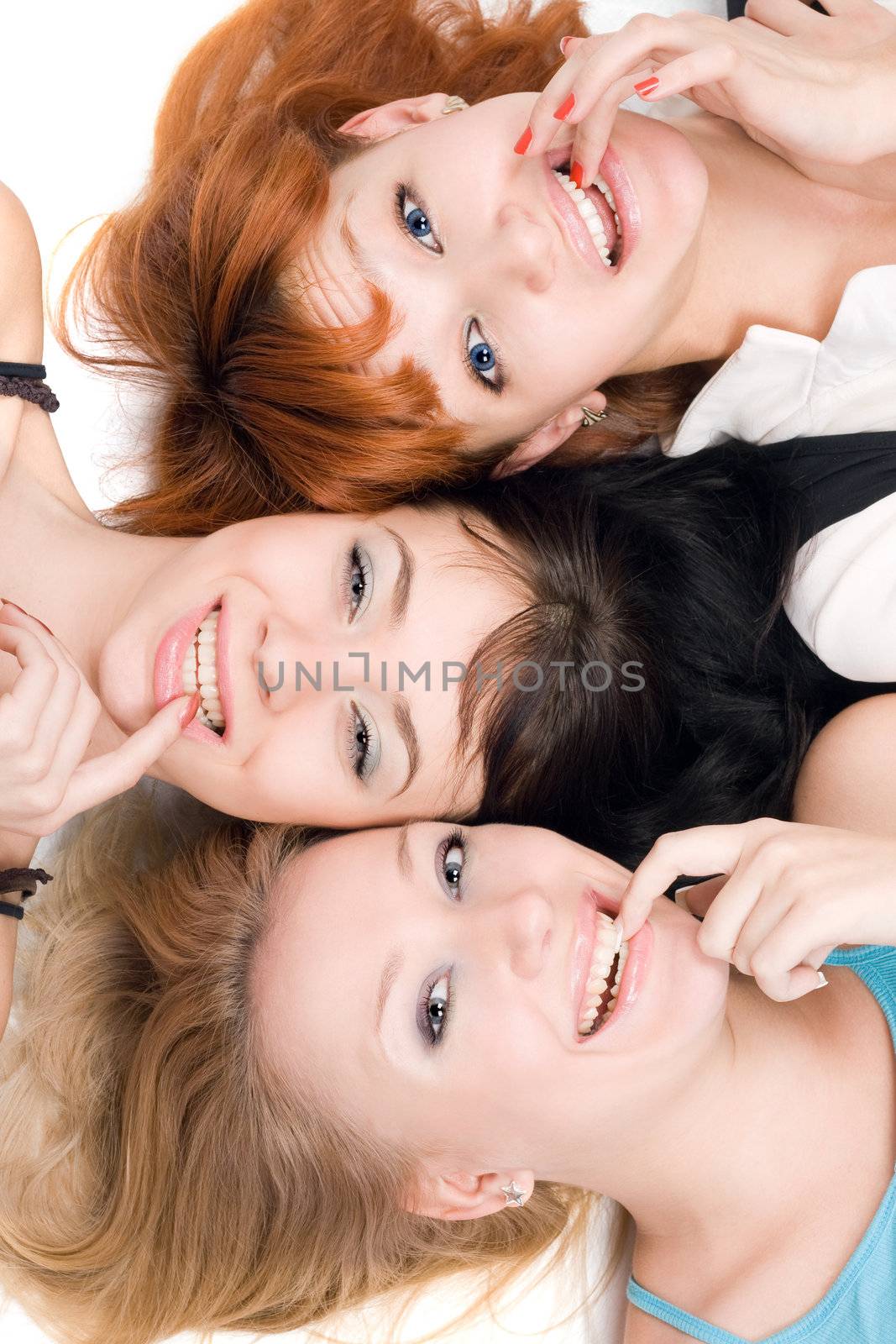 Portrait of three smiling young women lying on white background